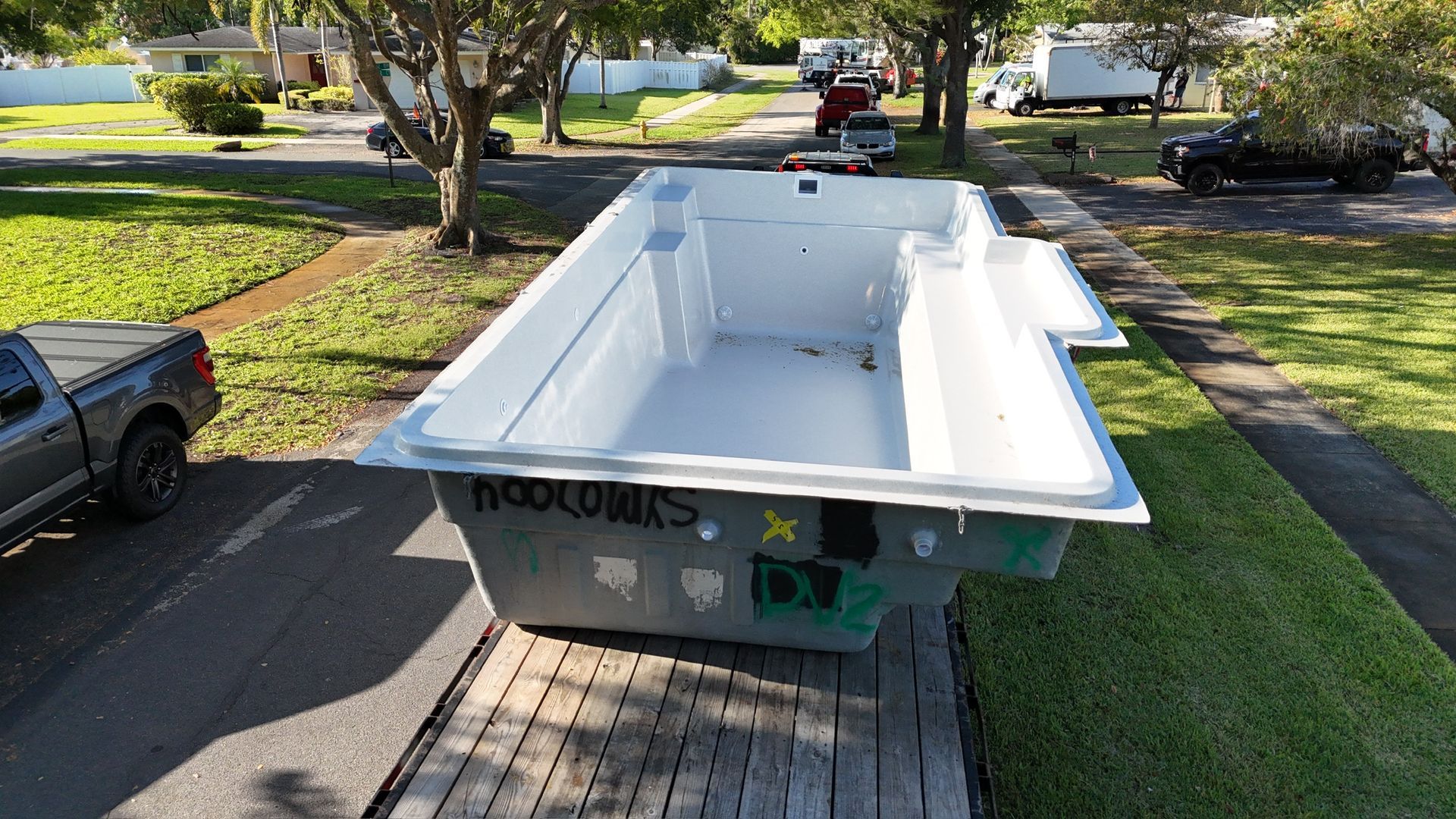 A large white swimming pool is sitting on top of a wooden deck.