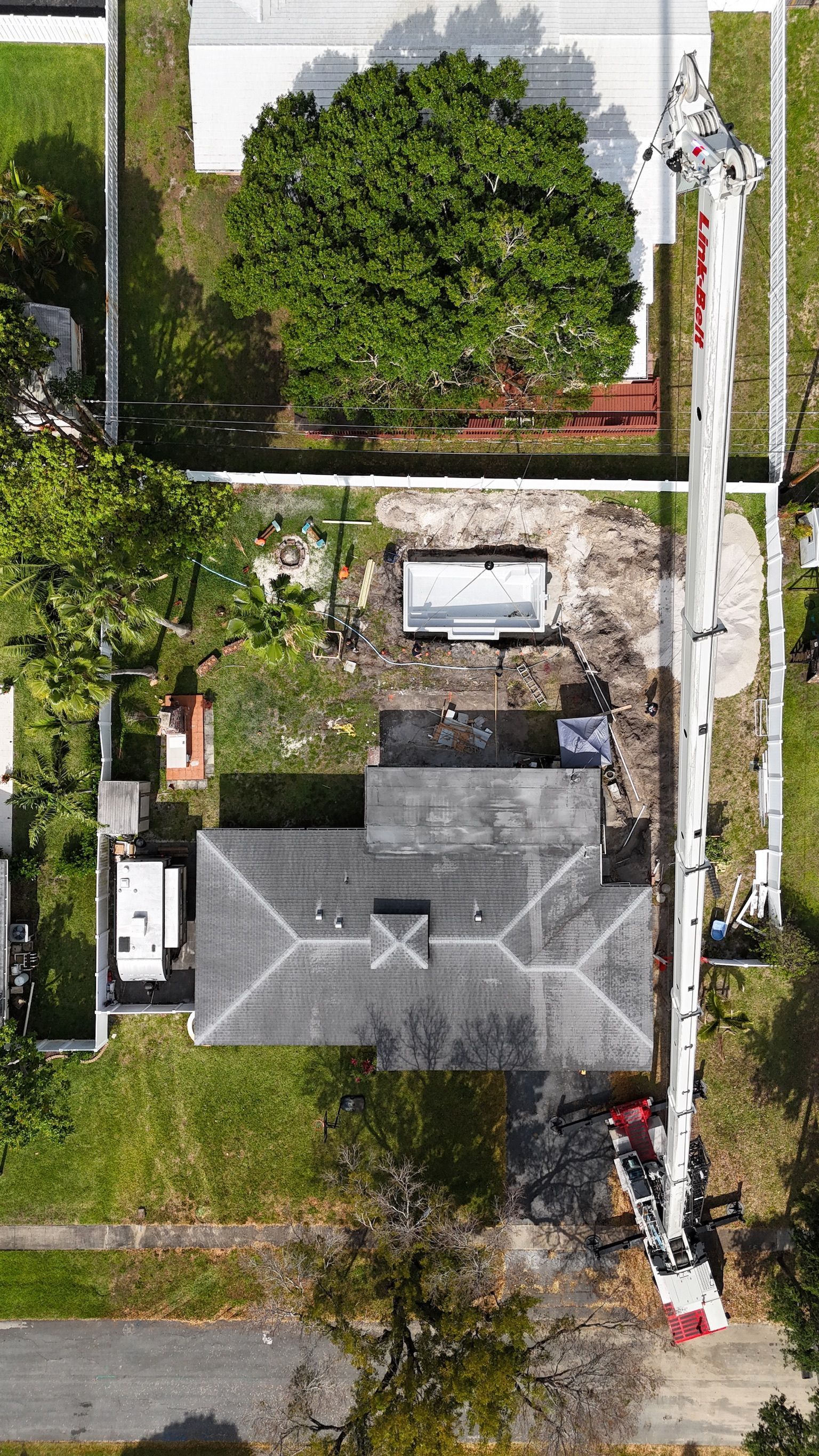 An aerial view of a house with a crane in front of it.