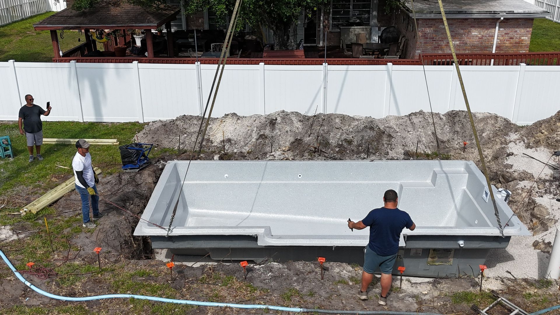 A group of men are working on a swimming pool in a backyard.