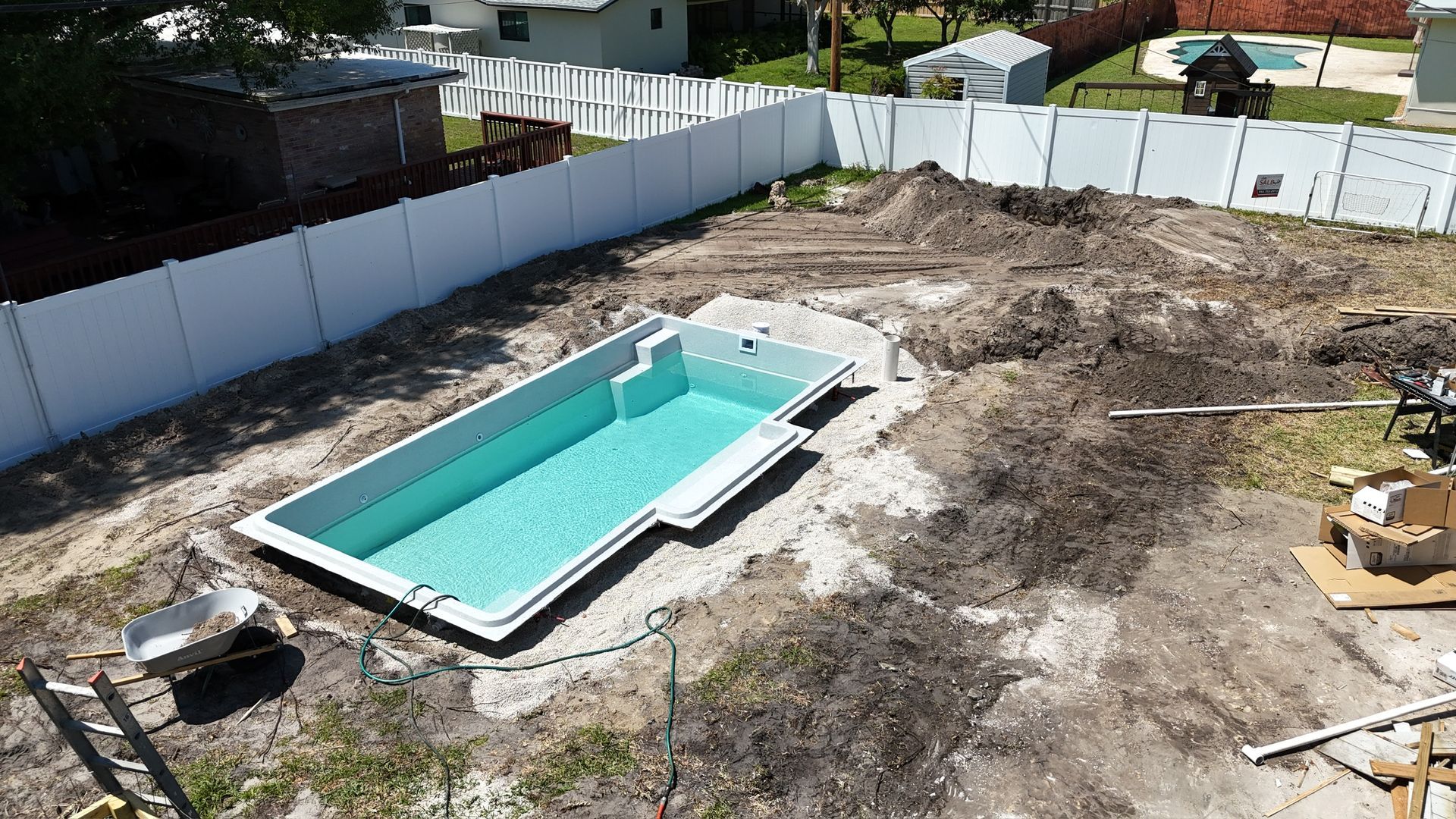 An aerial view of a swimming pool being built in a backyard.