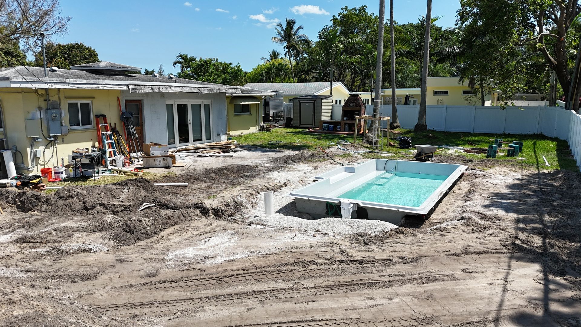 A swimming pool is being built in the backyard of a house.