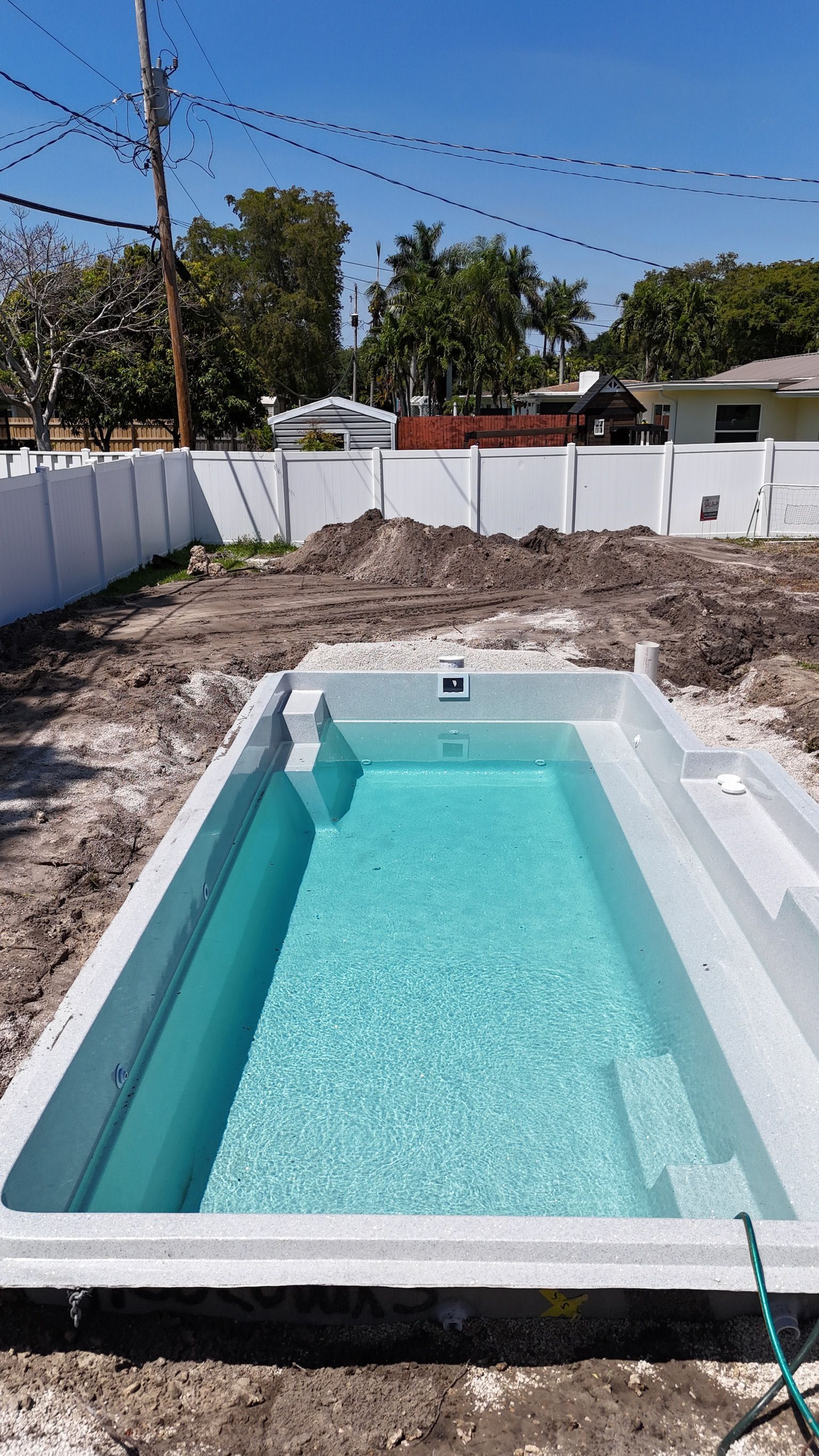 A swimming pool is being built in the backyard of a house.