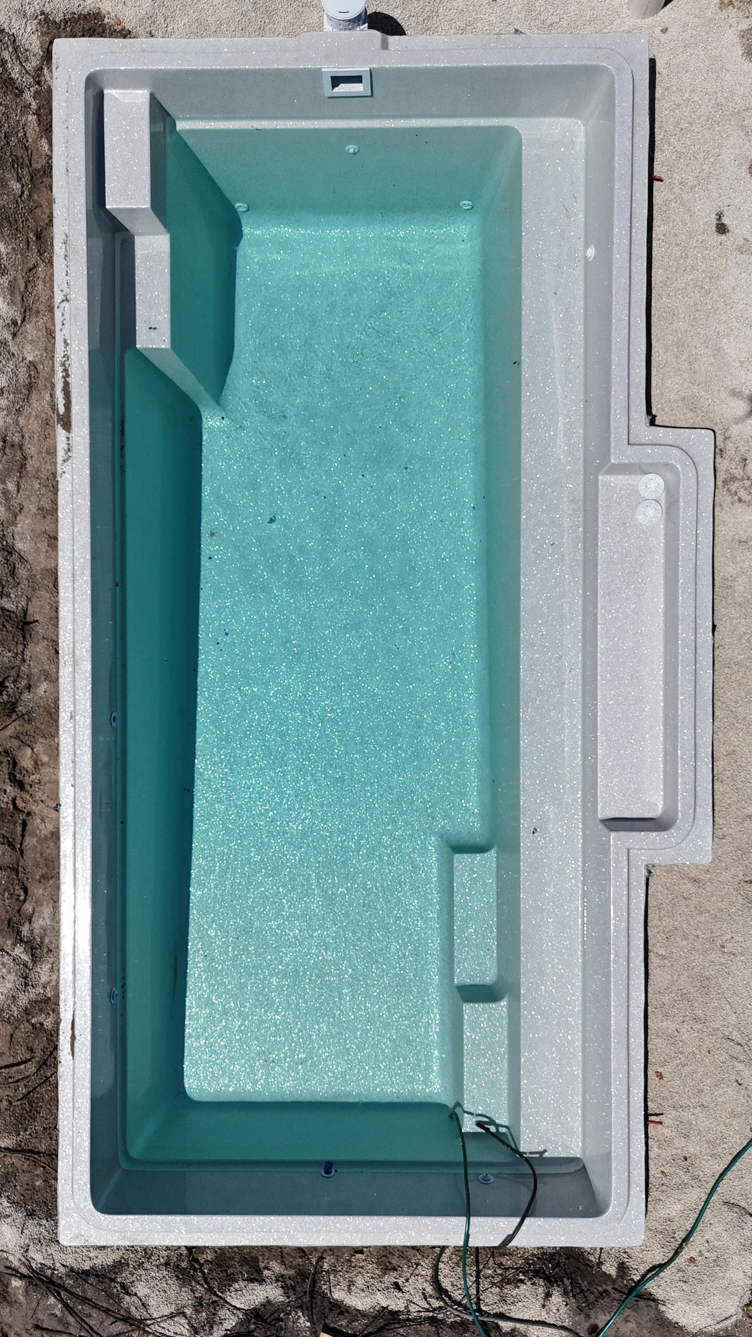 An aerial view of a swimming pool sitting on top of a dirt field.