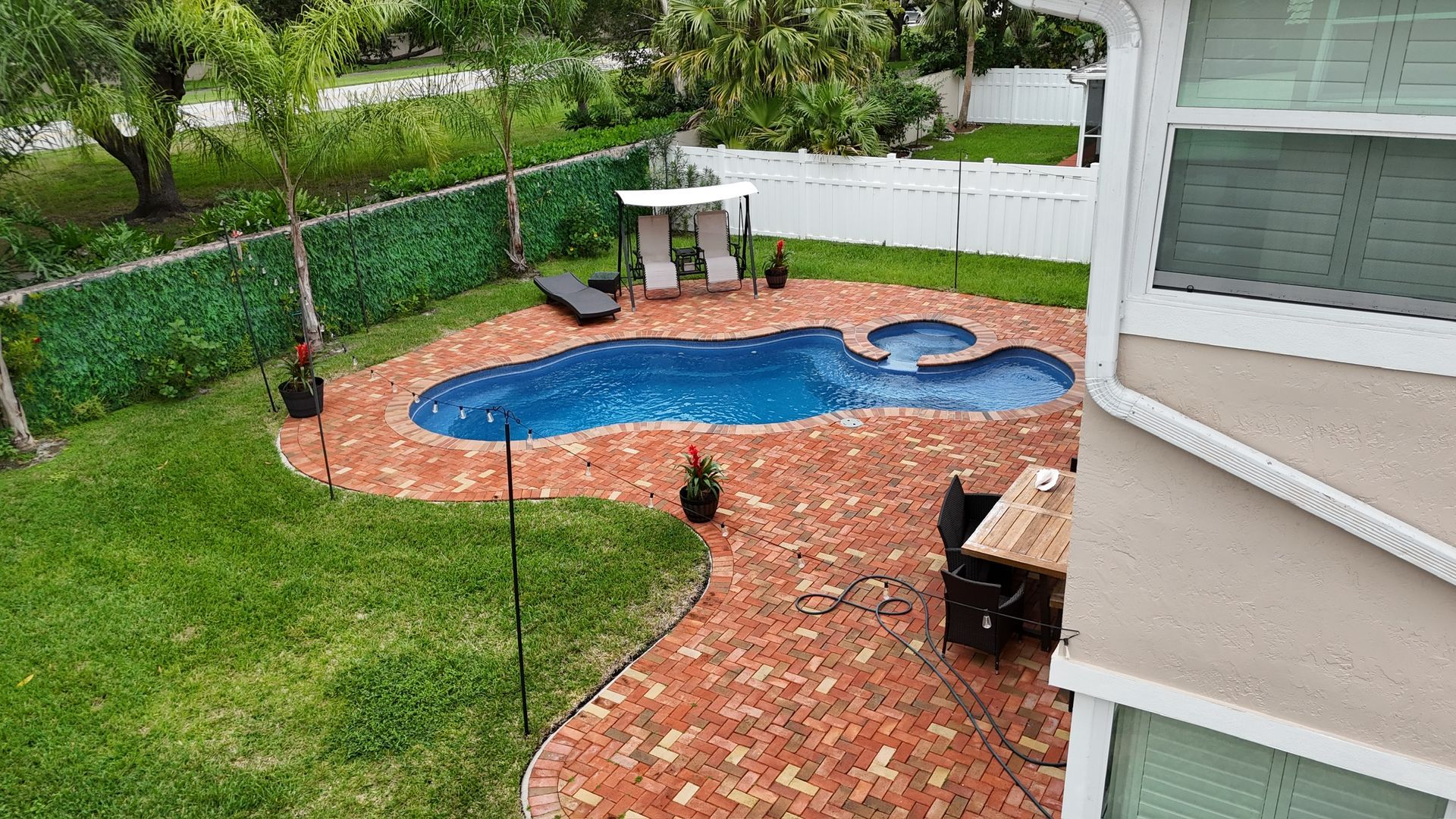 There is a large swimming pool in the backyard of a house.