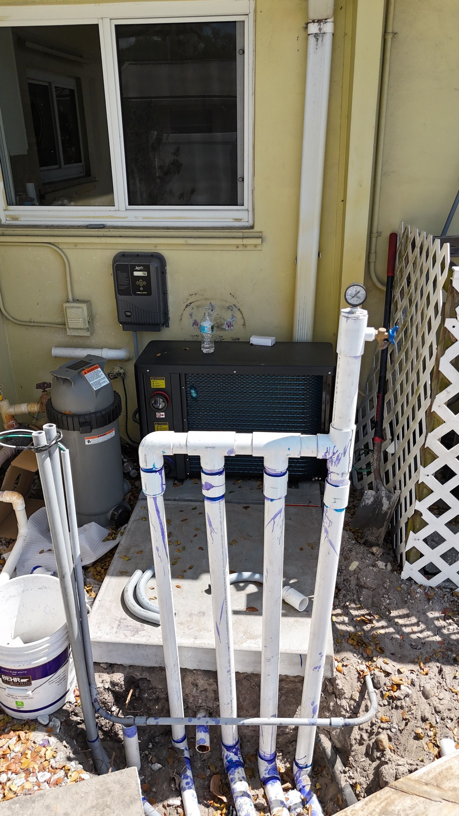 A swimming pool heater is being installed in the backyard of a house.