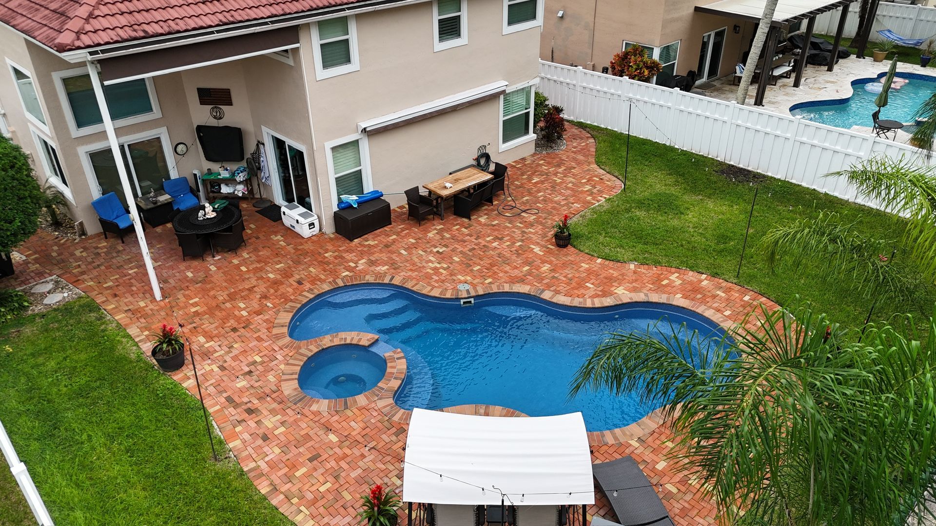An aerial view of a house with a large swimming pool in the backyard.