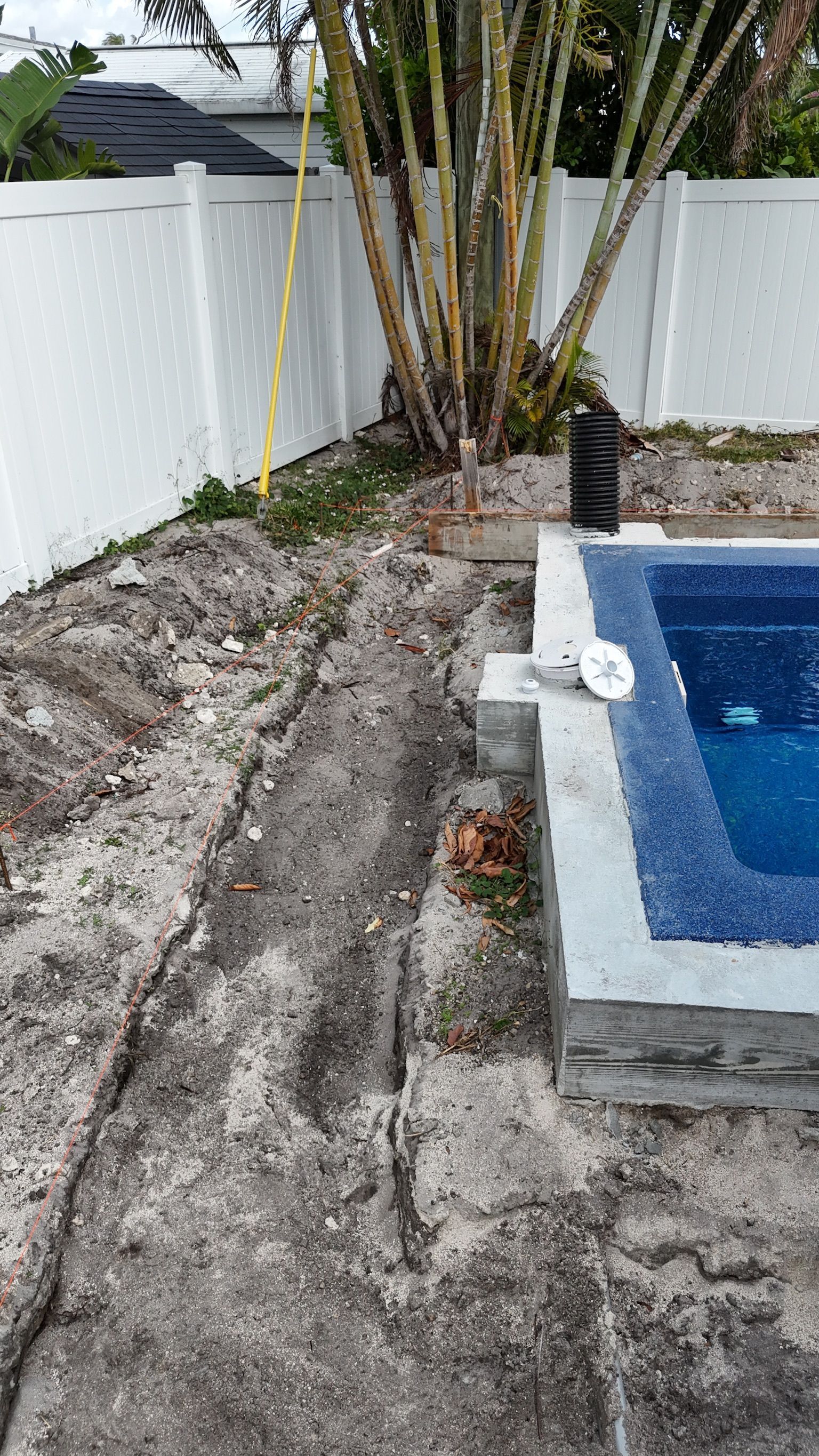 A swimming pool is being built in the backyard of a house.