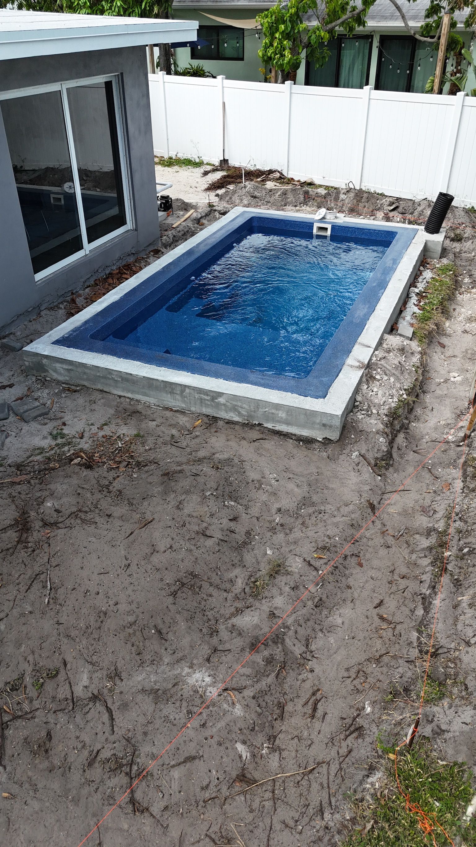 A small swimming pool is being built in the backyard of a house.