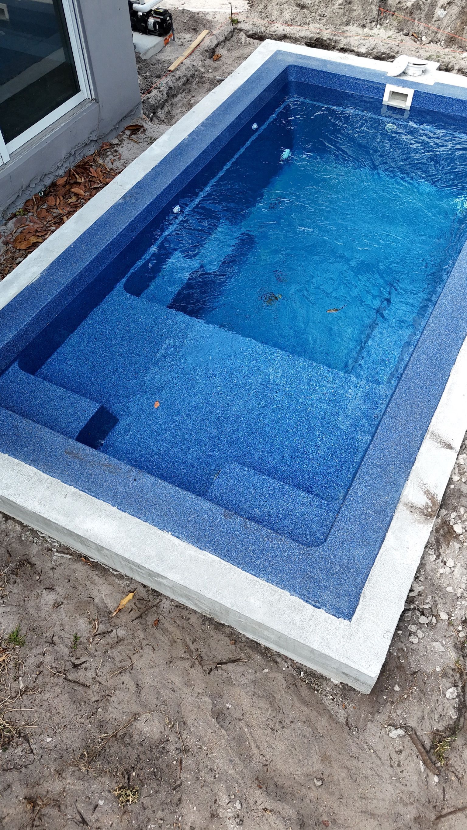A small swimming pool is sitting on top of a dirt field.