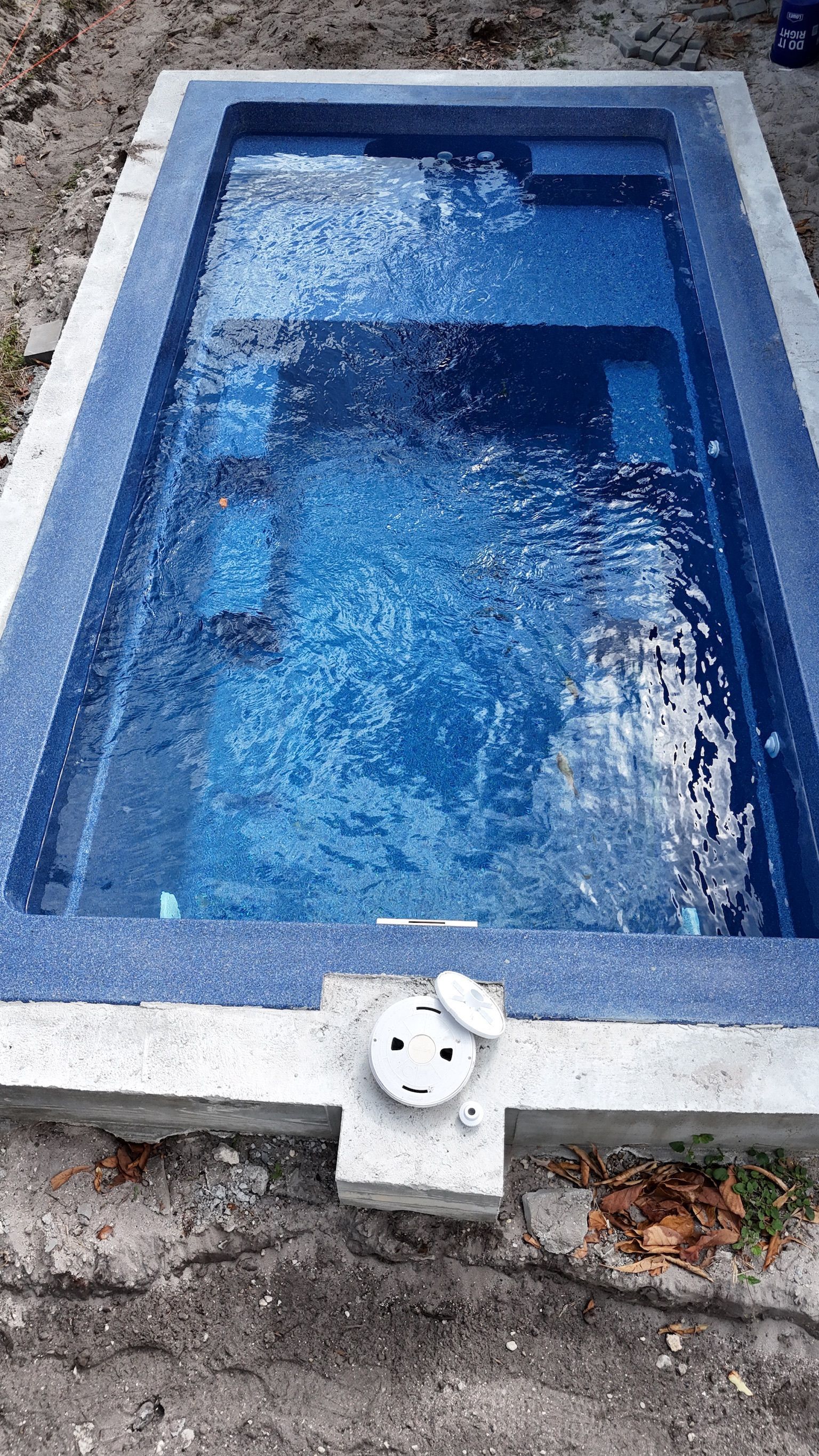 A small swimming pool is sitting on top of a dirt field.