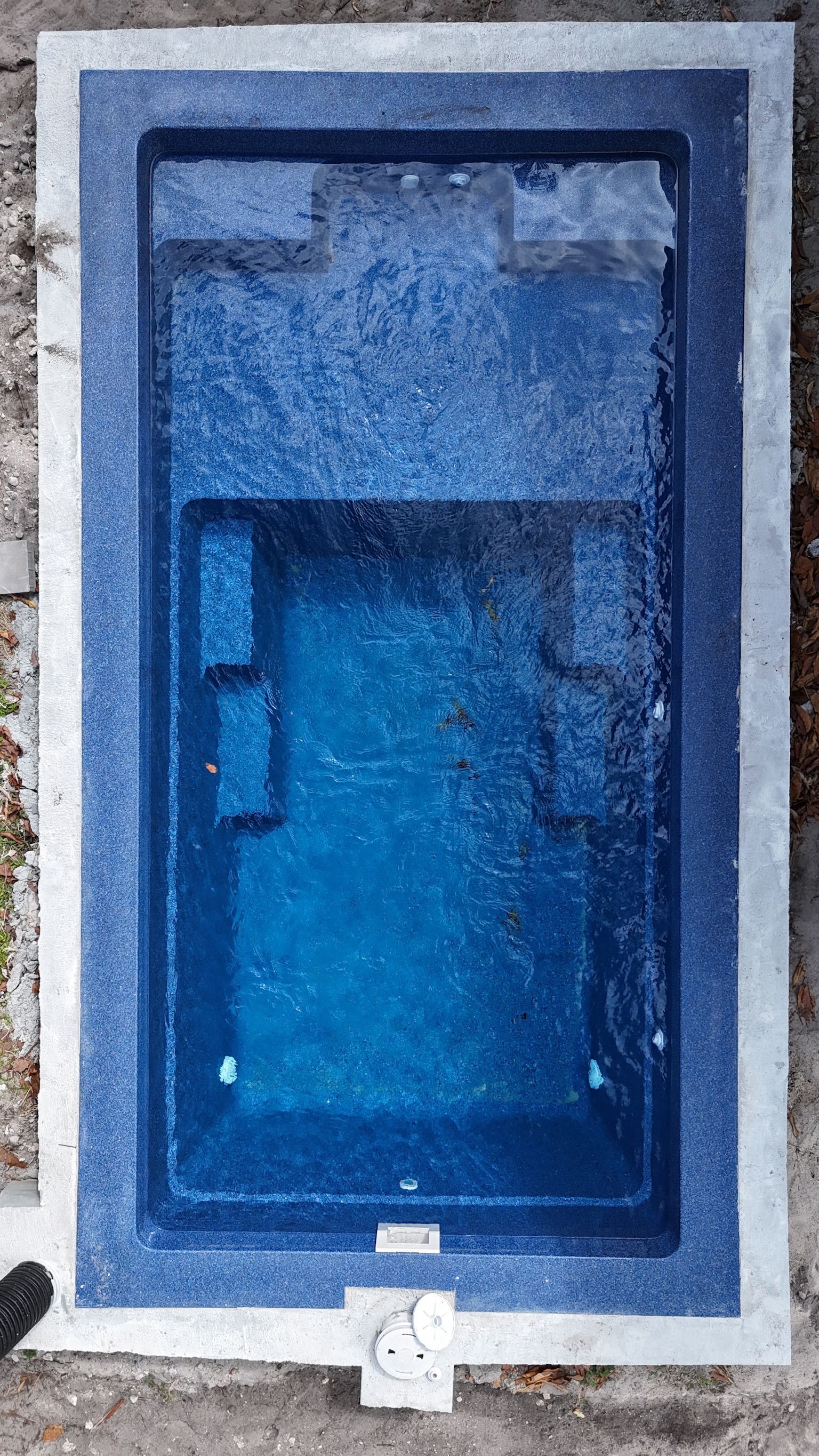 A large blue swimming pool is sitting on top of a concrete surface.