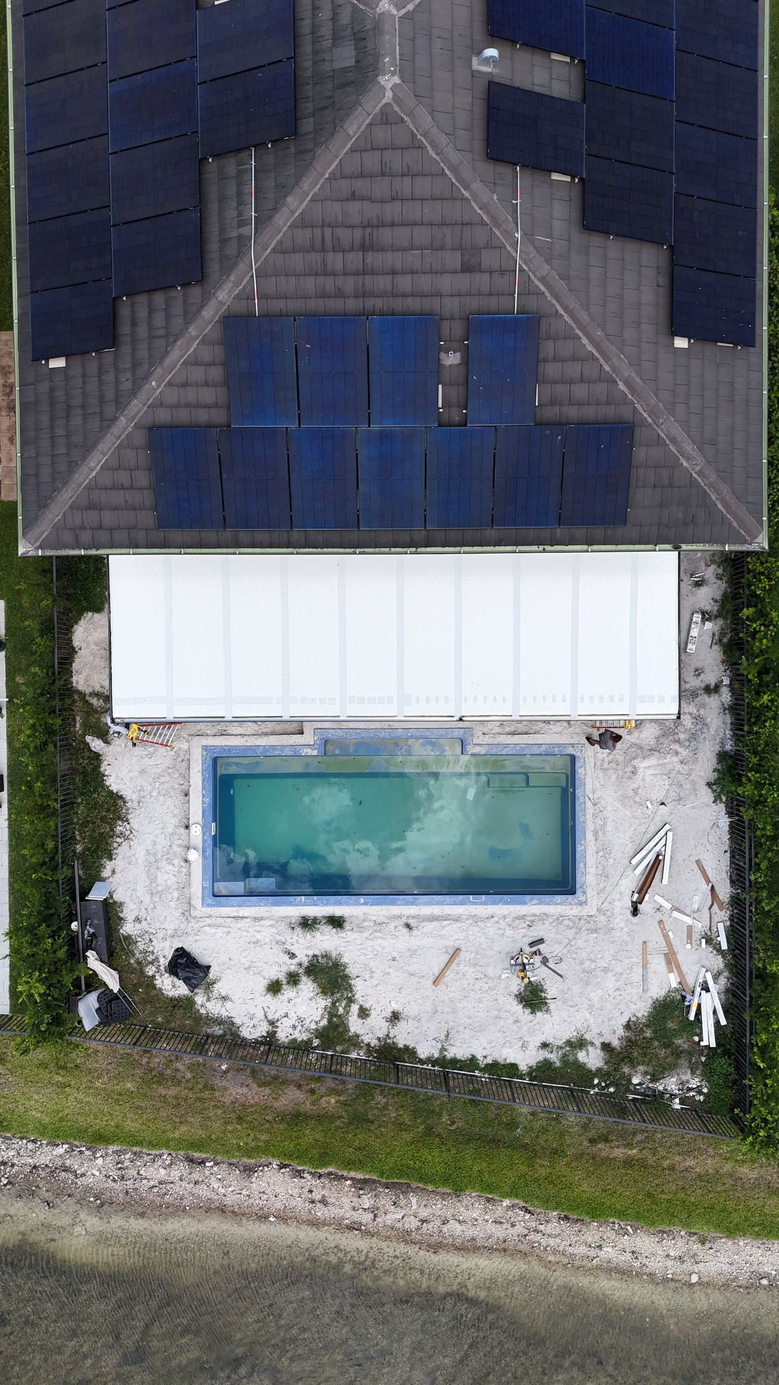 An aerial view of a house with a pool and solar panels on the roof.