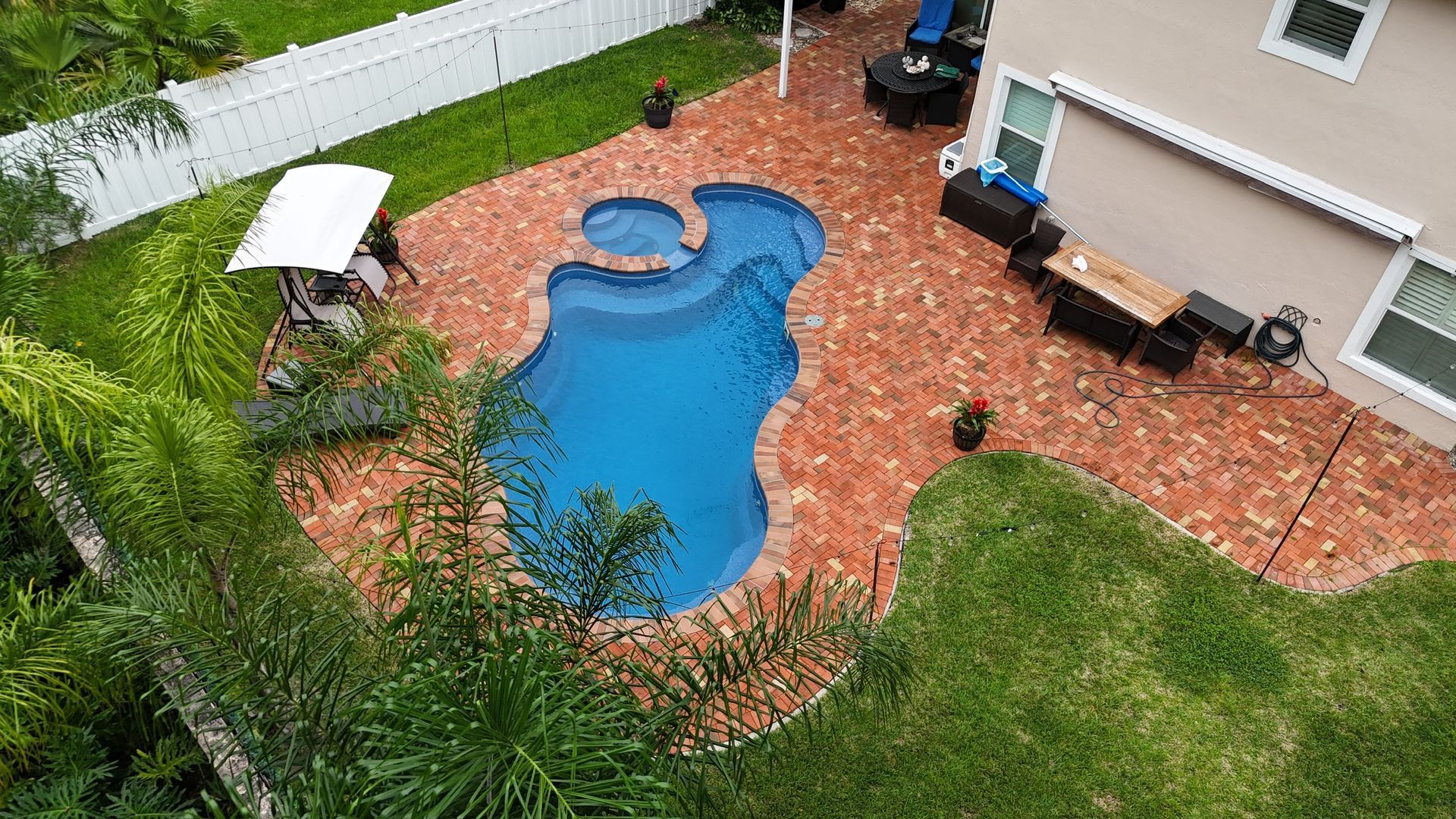An aerial view of a large swimming pool in the backyard of a house.