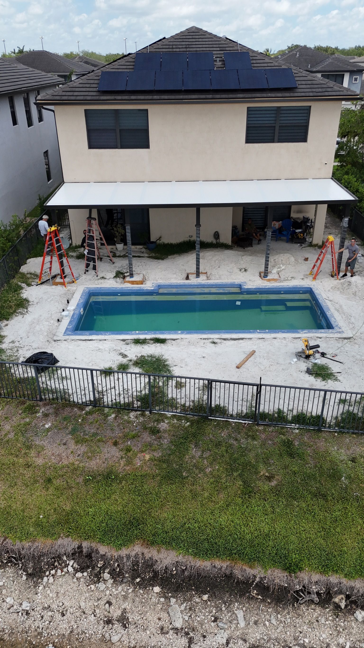 An aerial view of a house with a swimming pool and solar panels on the roof.
