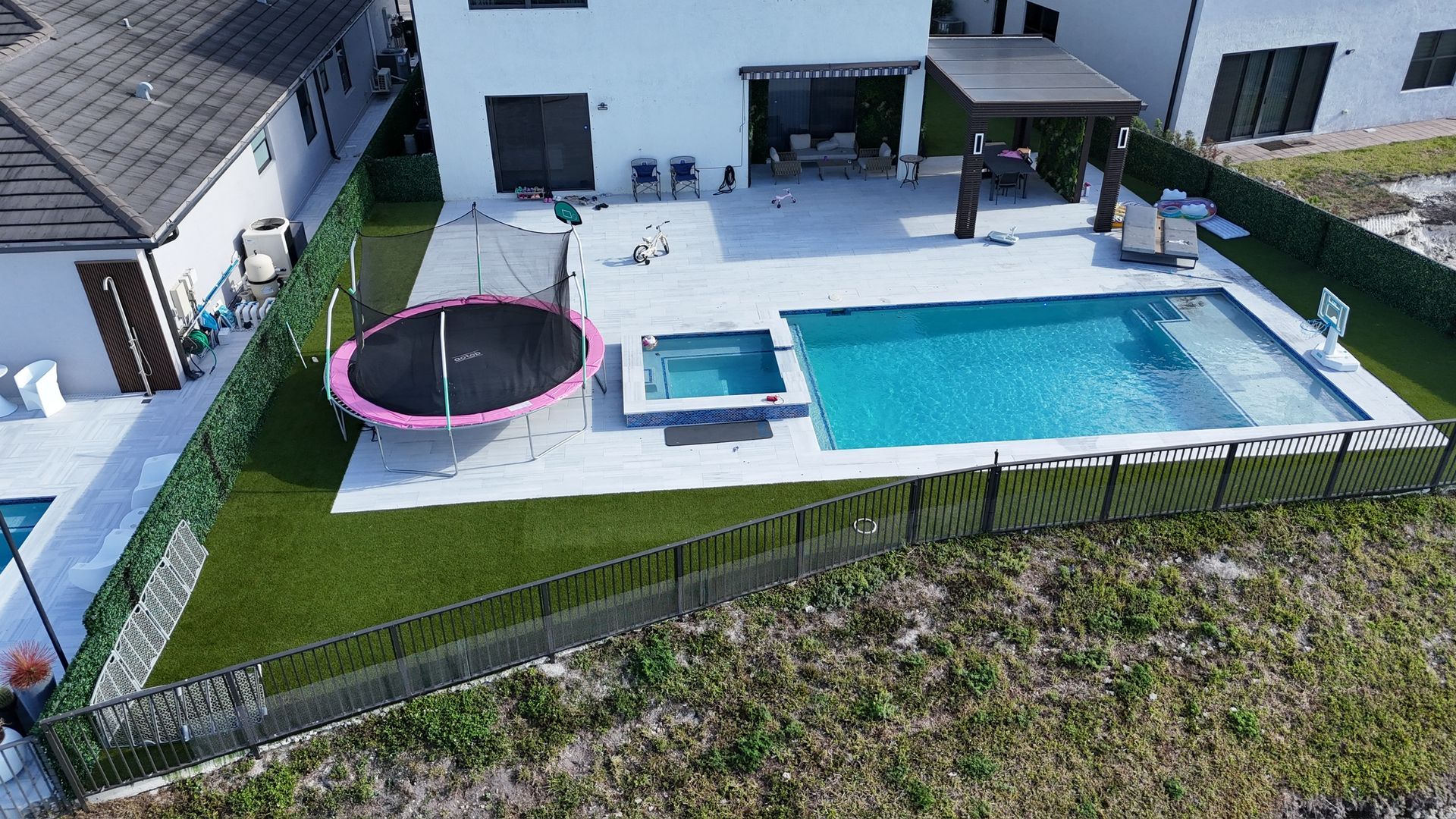 An aerial view of a house with a large swimming pool and trampoline.