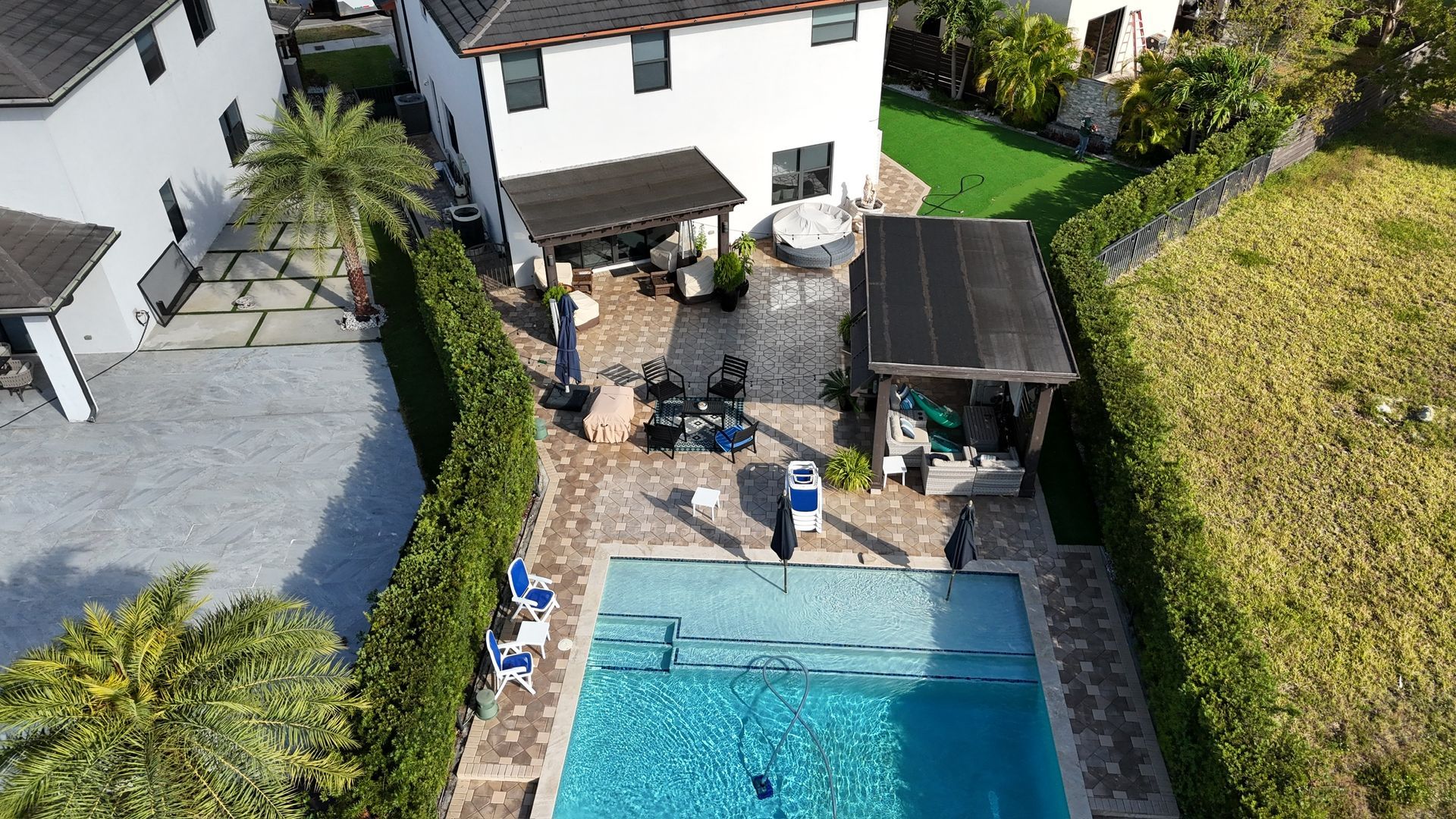 An aerial view of a house with a swimming pool in front of it.