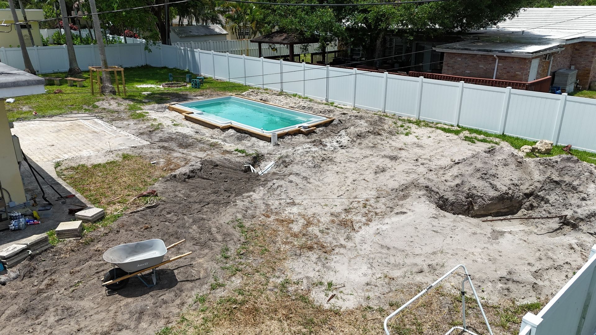 An aerial view of a swimming pool being built in a backyard.