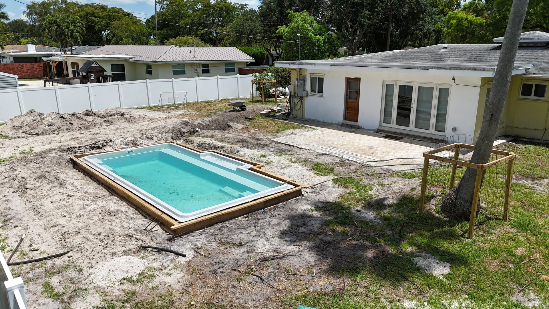 A swimming pool is being built in the backyard of a house.