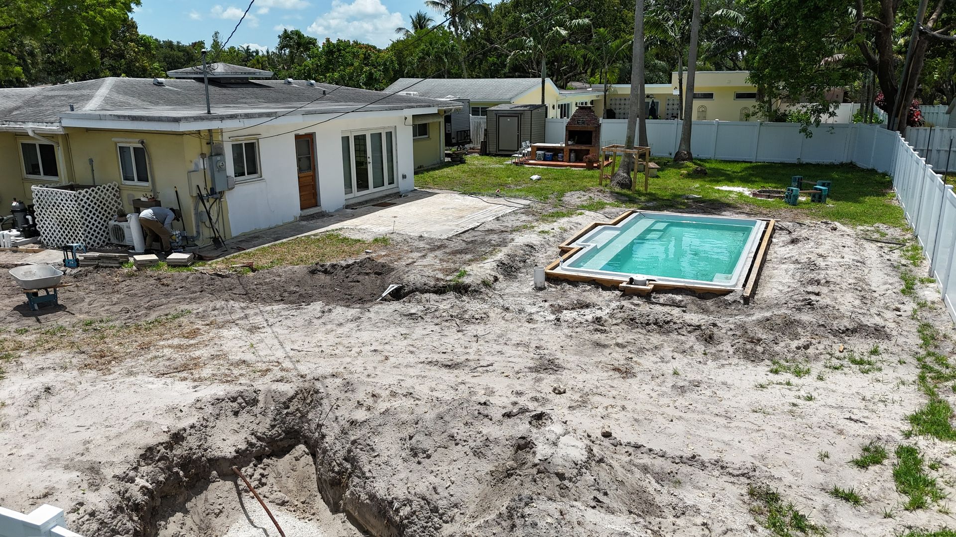 A swimming pool is being built in the backyard of a house.