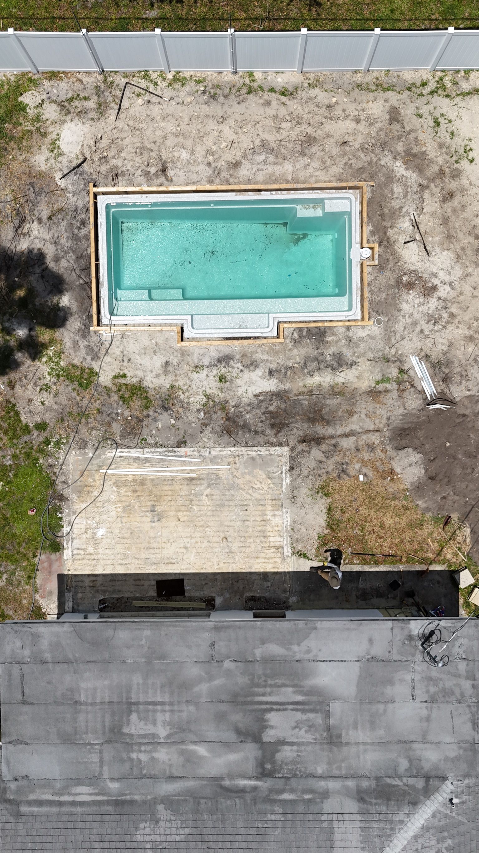 An aerial view of a swimming pool being built in a backyard.