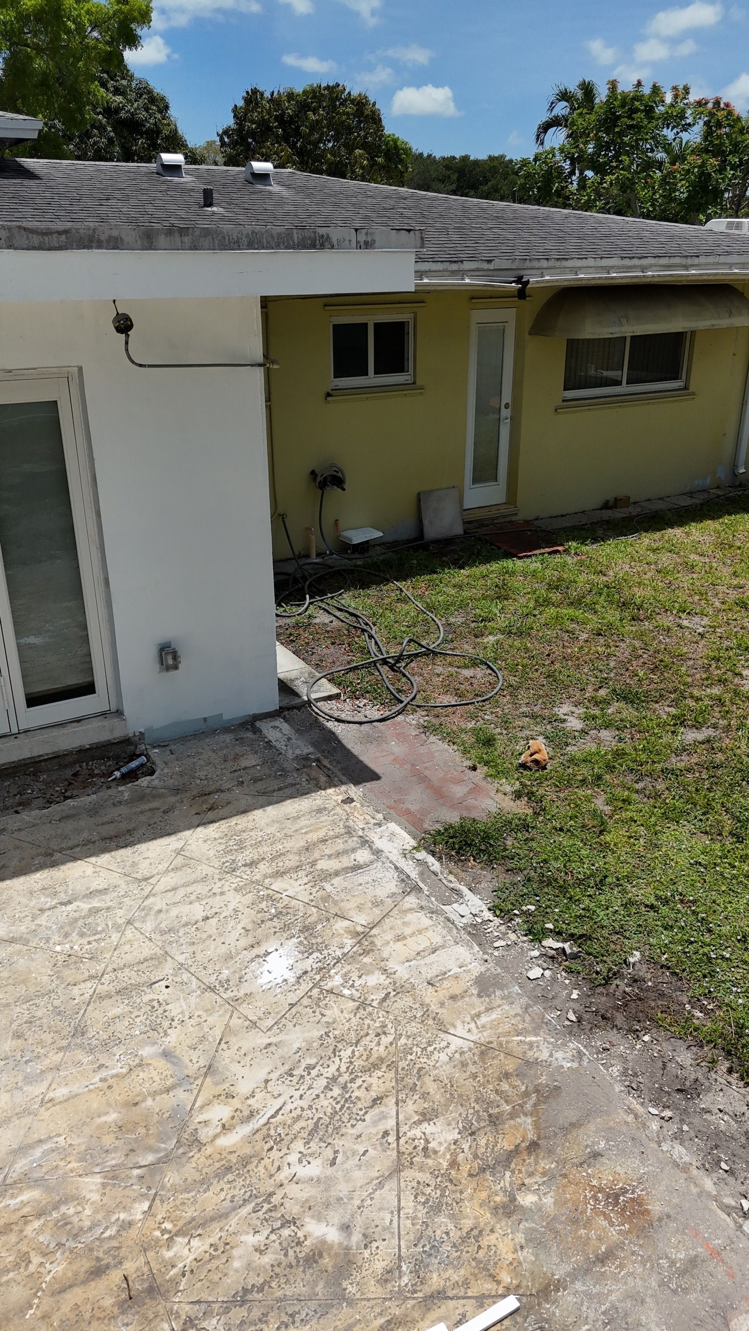 A yellow house with a white roof and a patio in front of it.