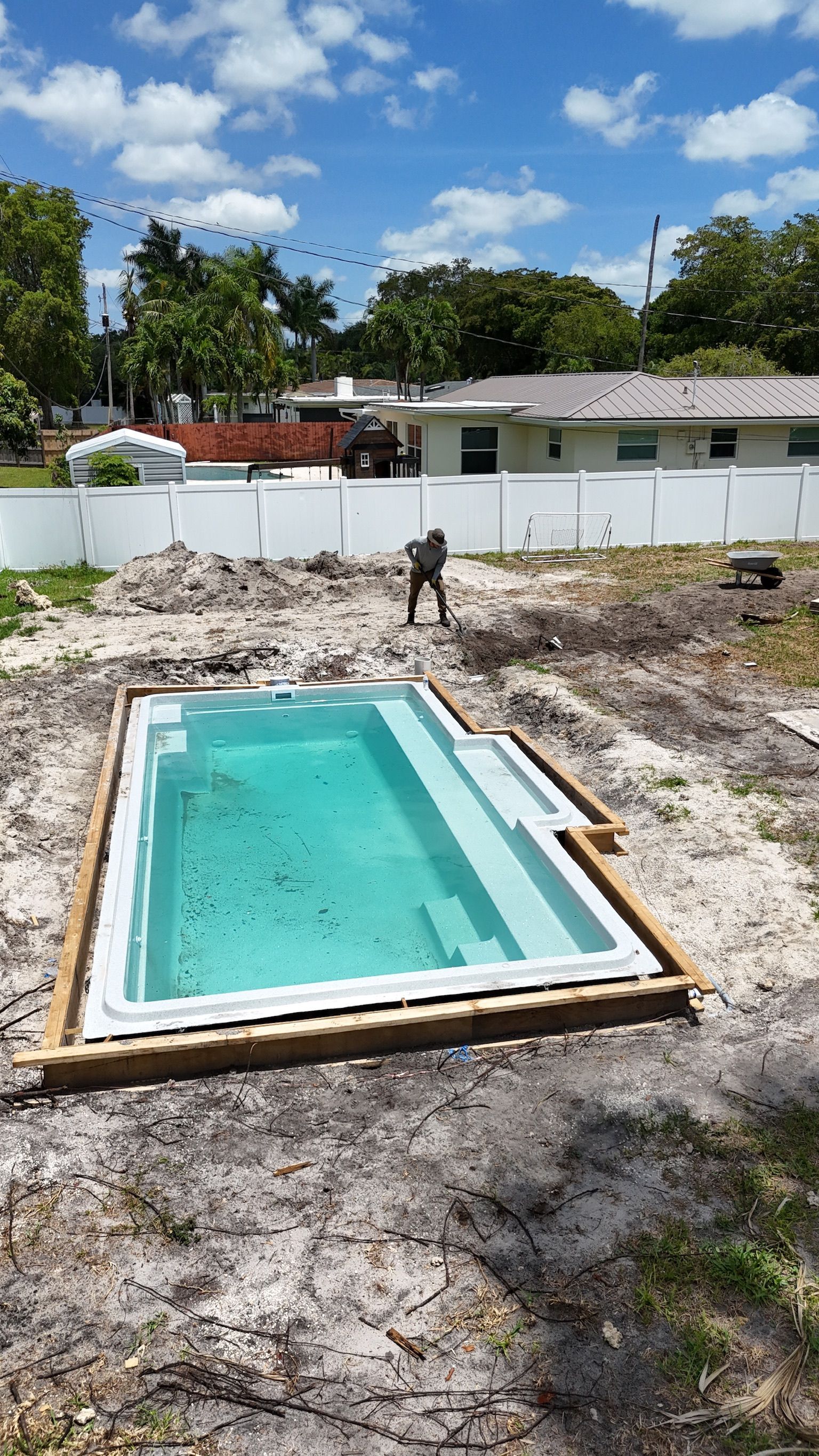 A swimming pool is being built in the backyard of a house.