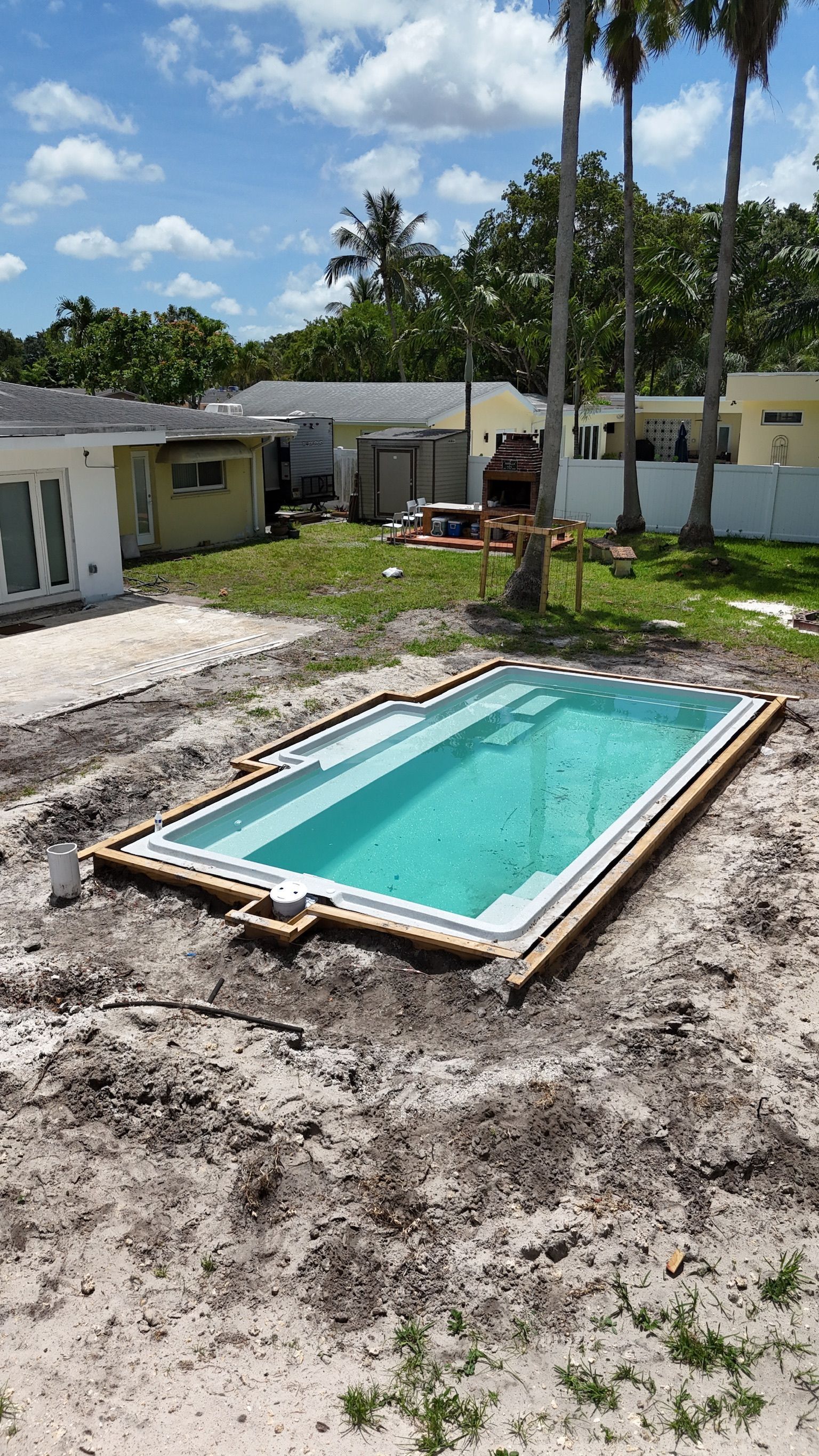 A swimming pool is being built in the backyard of a house.