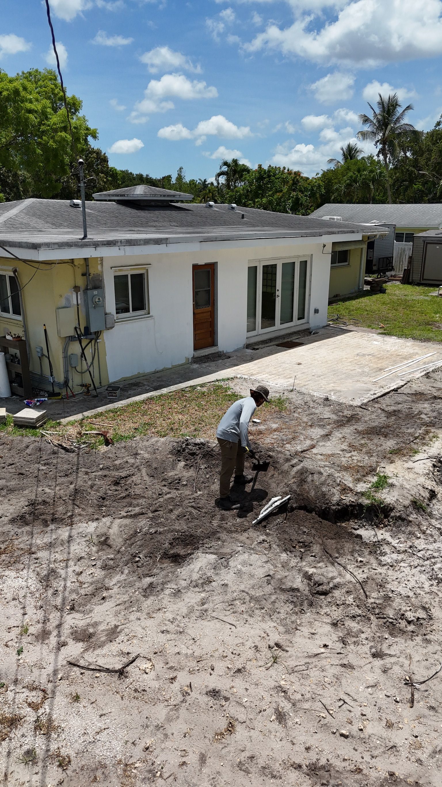 A man is digging in the dirt in front of a house.