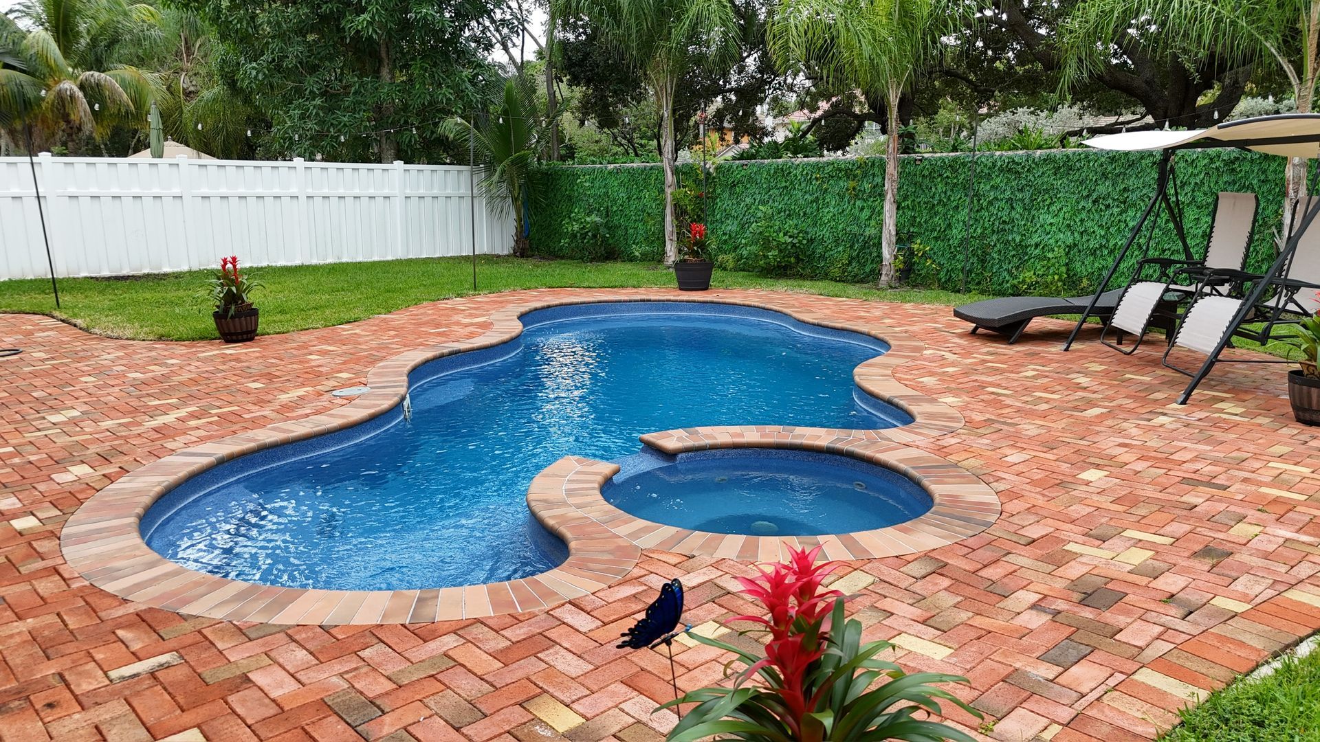 A large swimming pool with a hot tub in the backyard.