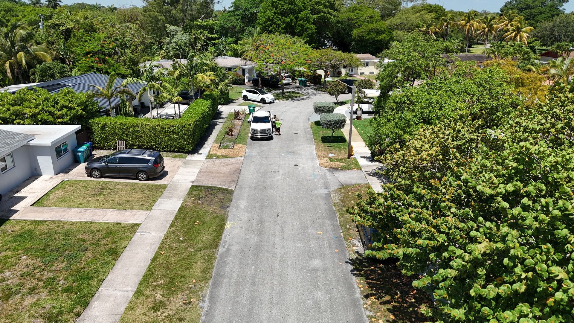 An aerial view of a residential street with cars driving down it.