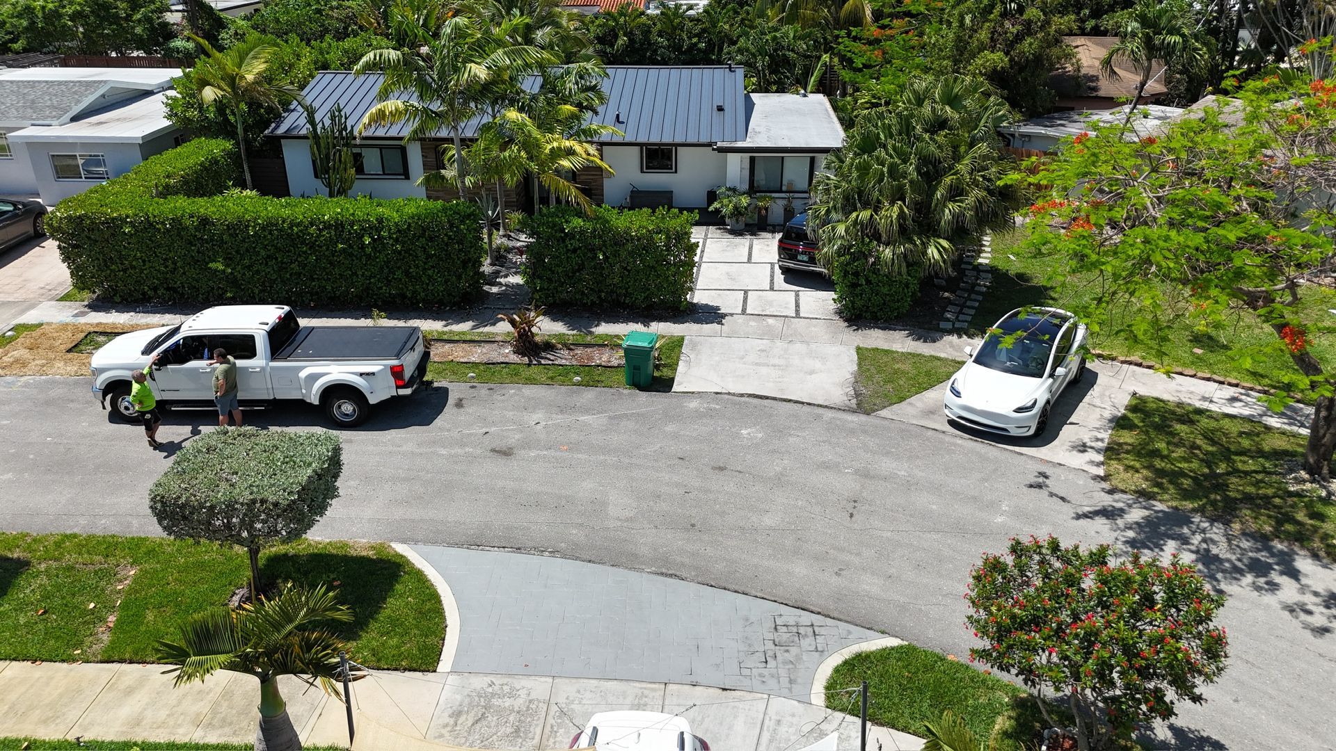 An aerial view of a residential neighborhood with a white truck parked in front of a house.