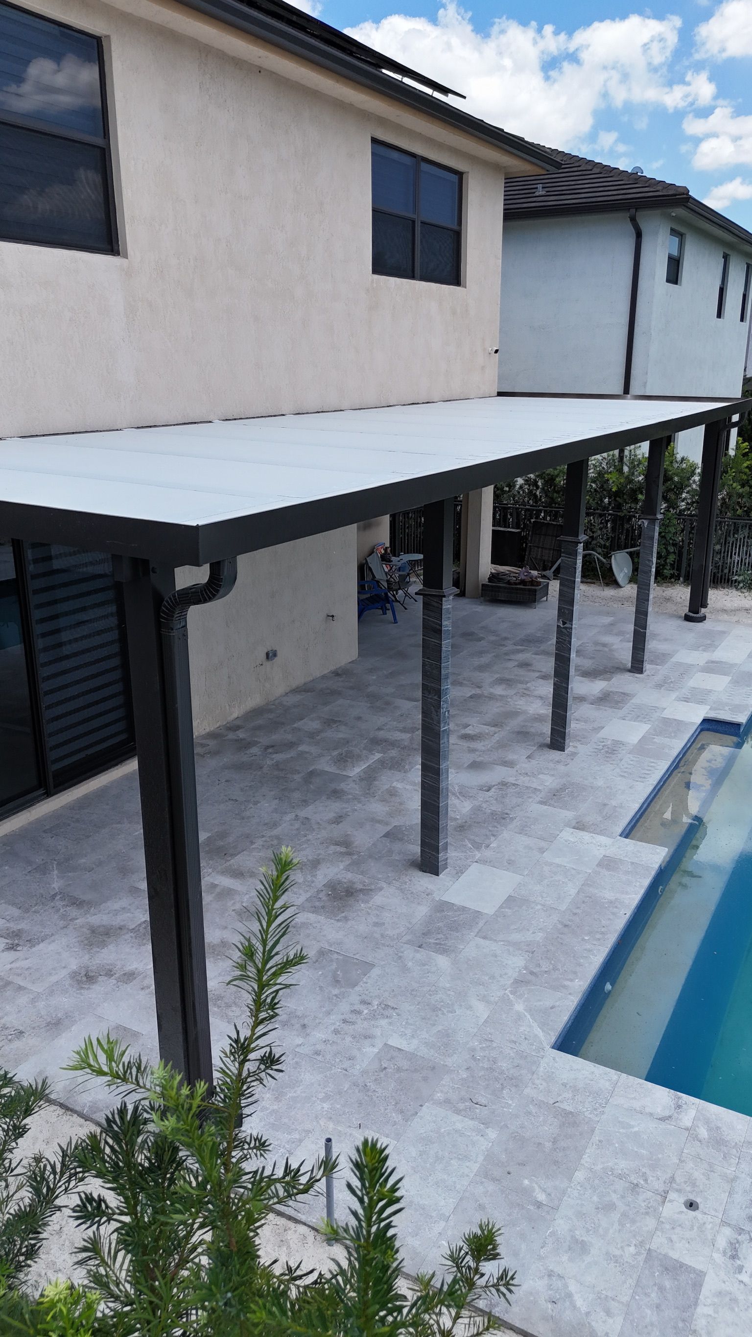 A house with a covered patio next to a pool.