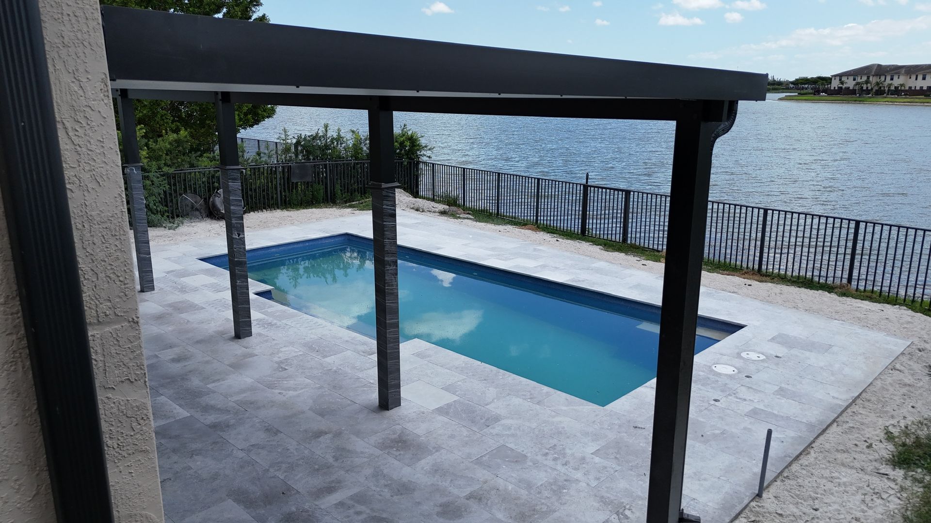 A swimming pool with a pergola overlooking a lake.