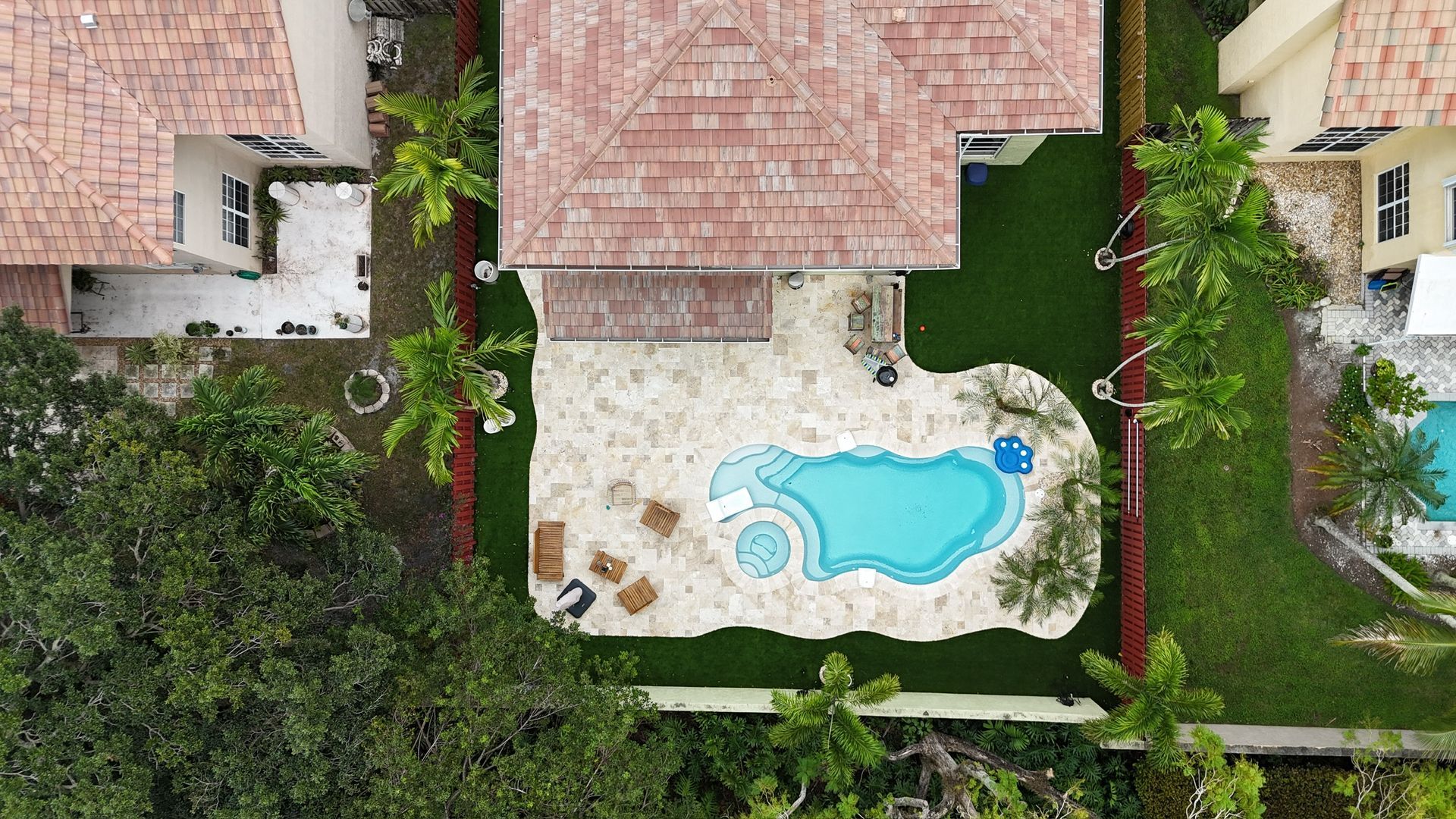 An aerial view of a house with a pool in the backyard surrounded by trees.