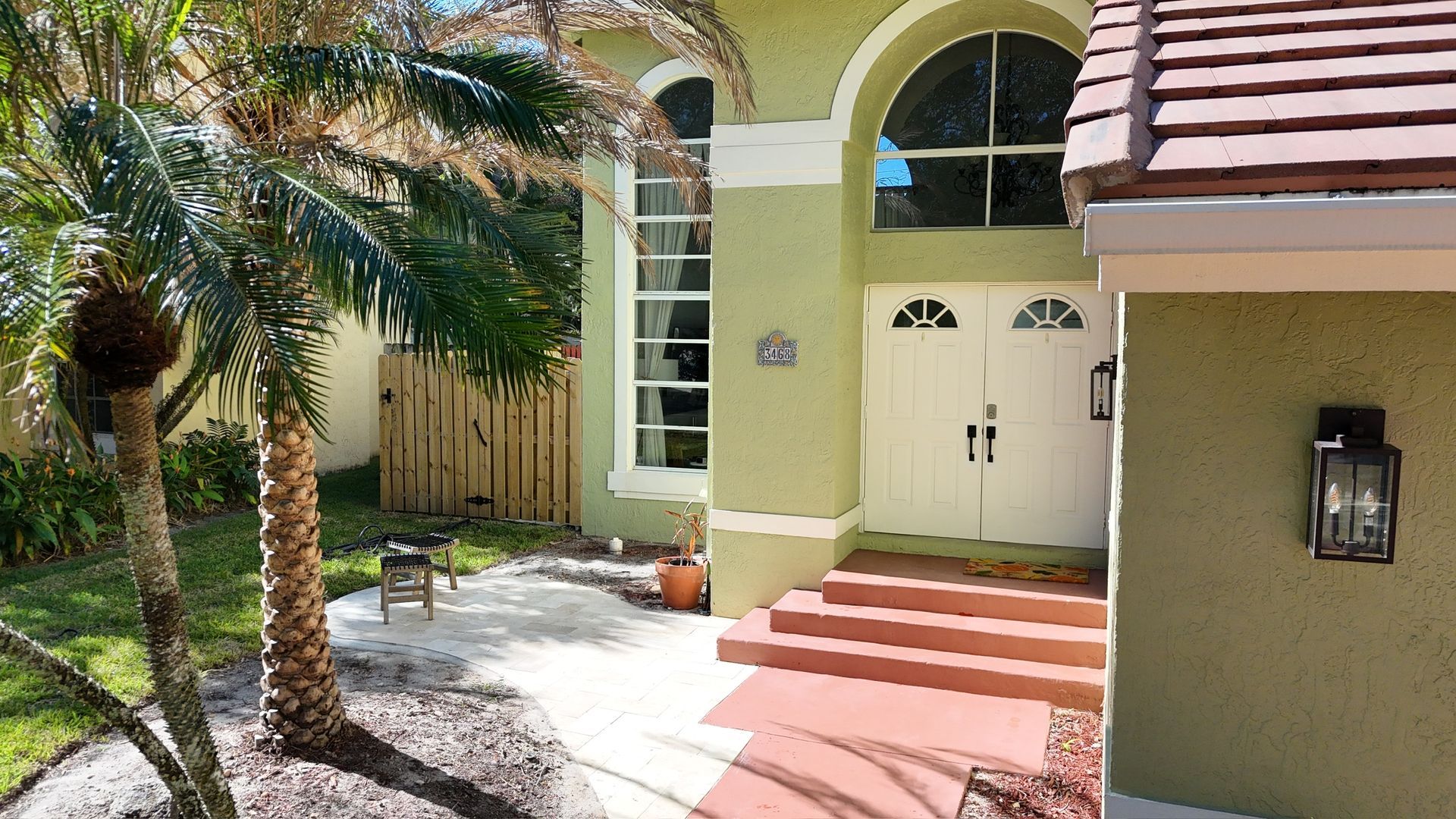 The front of a house with a palm tree in front of it.