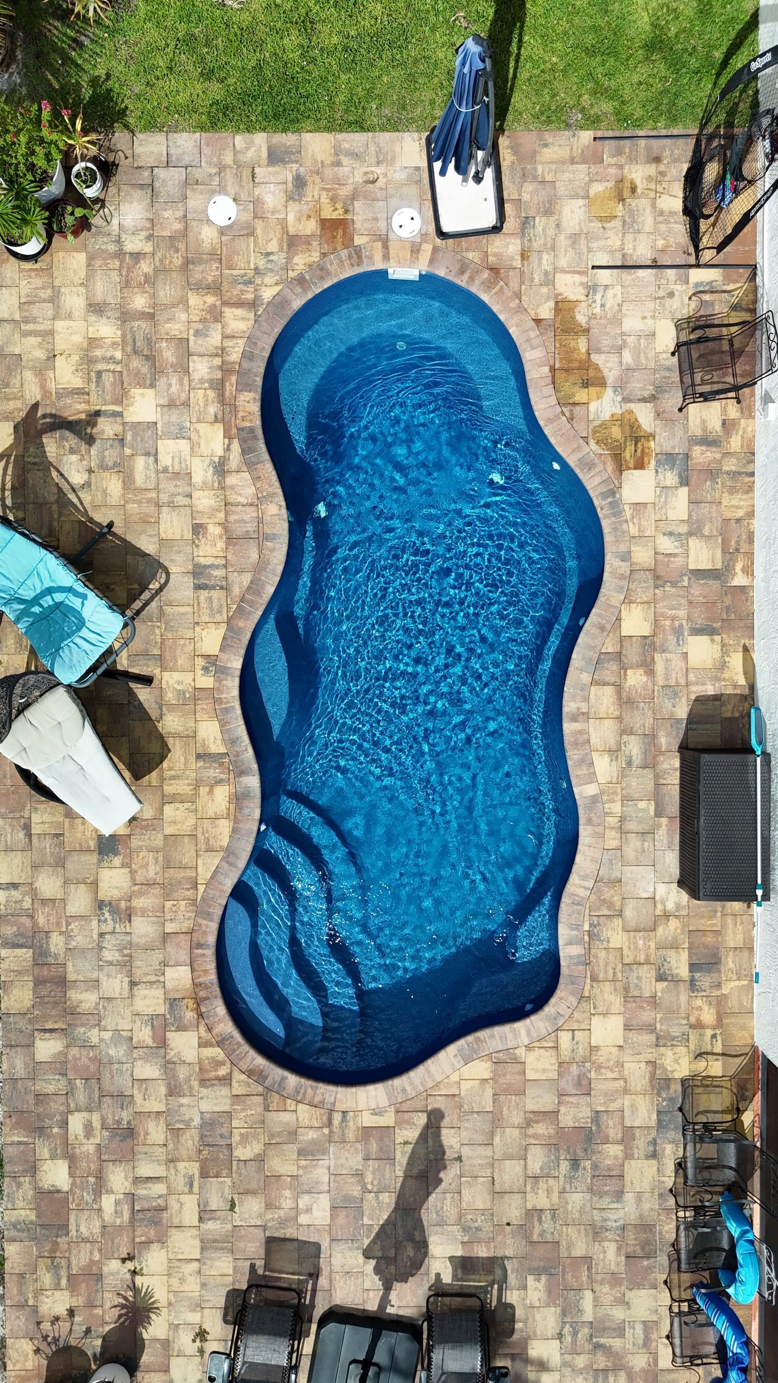 An aerial view of a large blue swimming pool in a backyard.