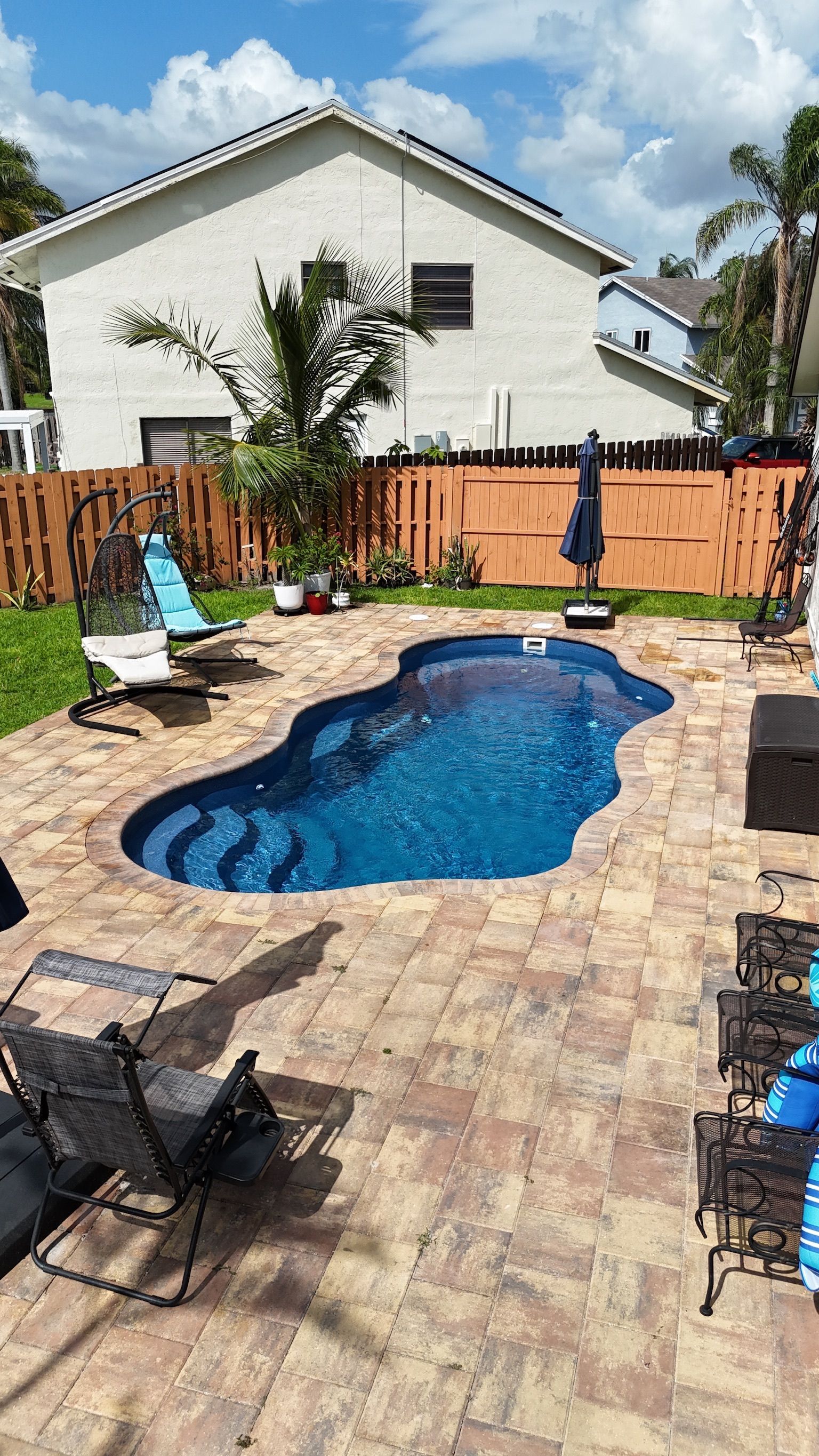 There is a large swimming pool in the backyard of a house.
