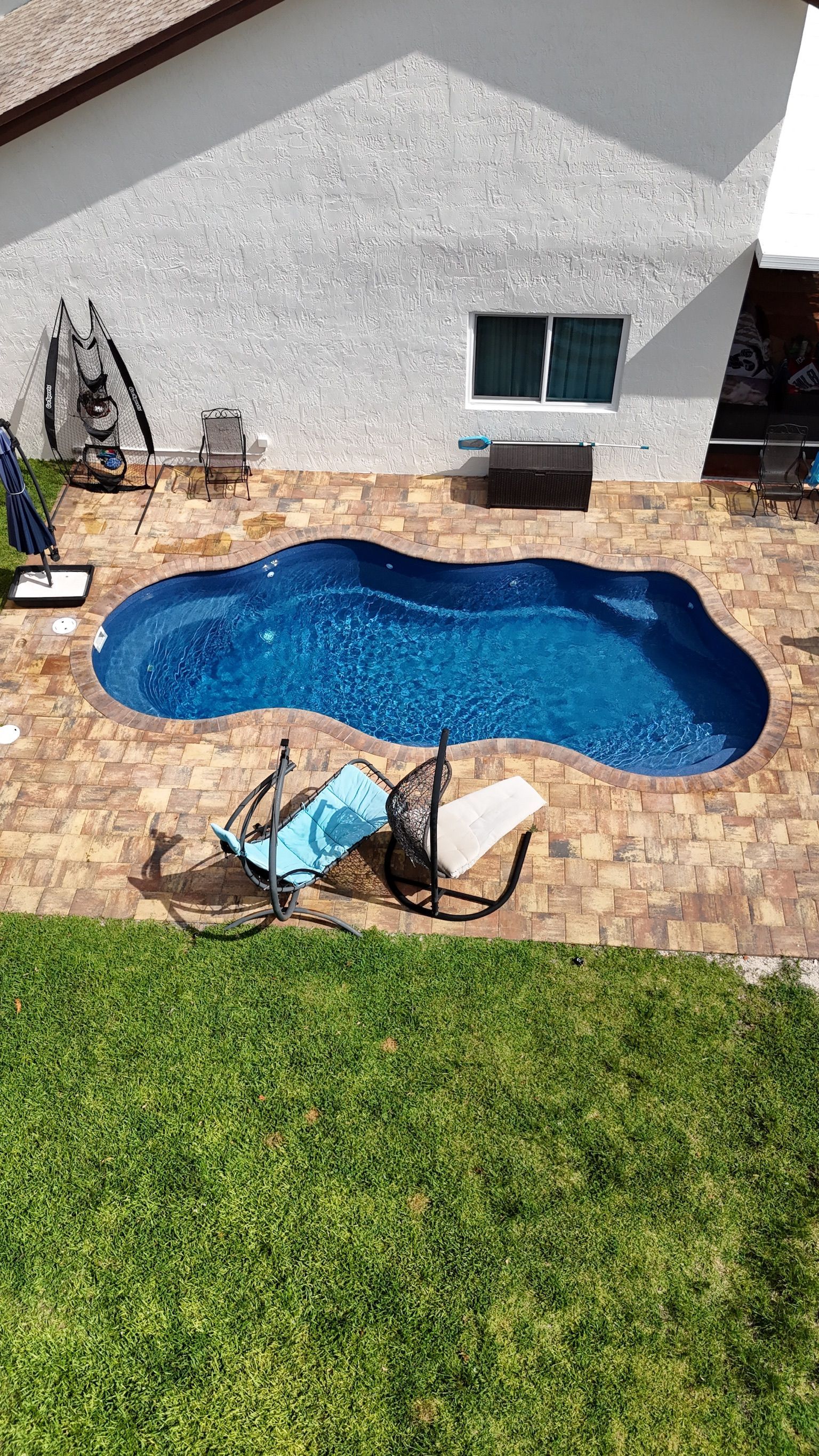 An aerial view of a large swimming pool in the backyard of a house.