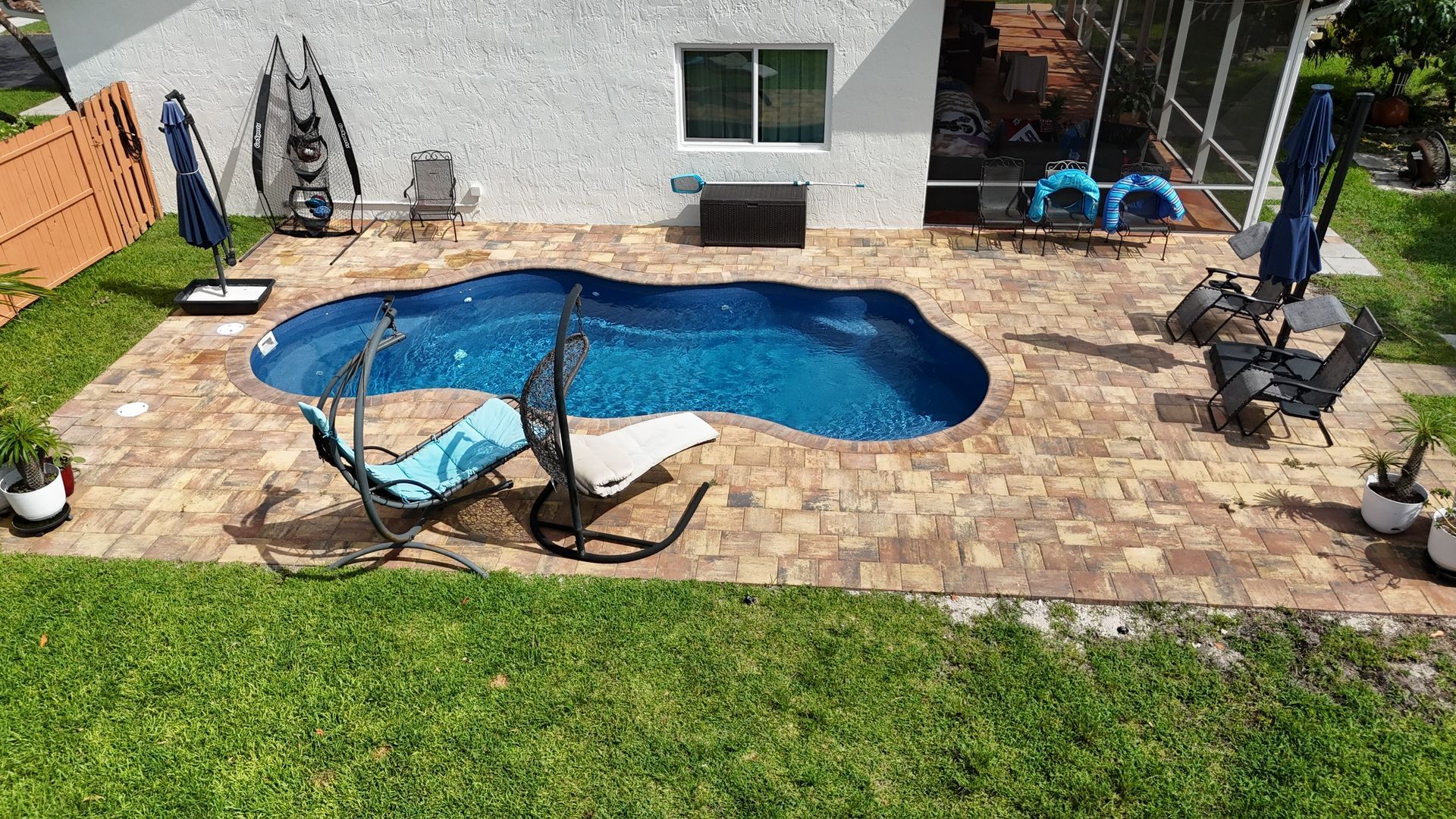 There is a large swimming pool in the backyard of a house.