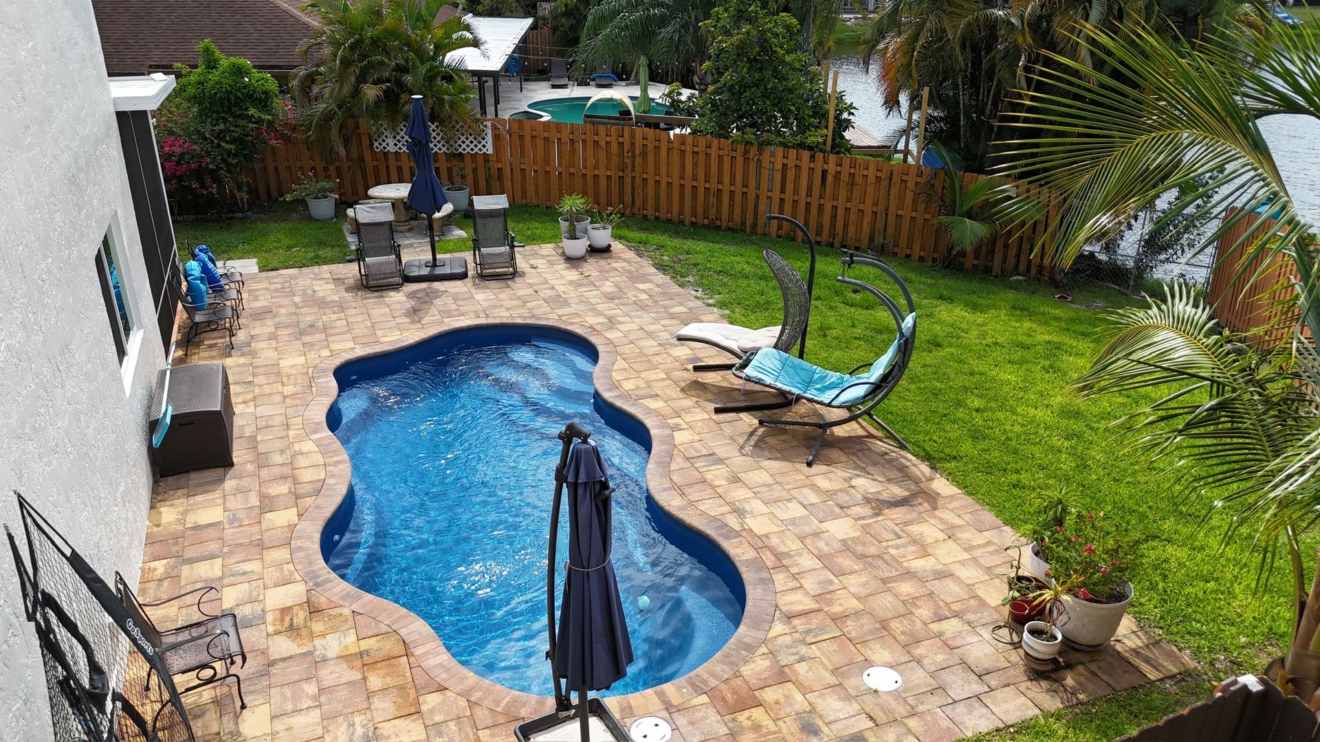 There is a large swimming pool in the backyard of a house.