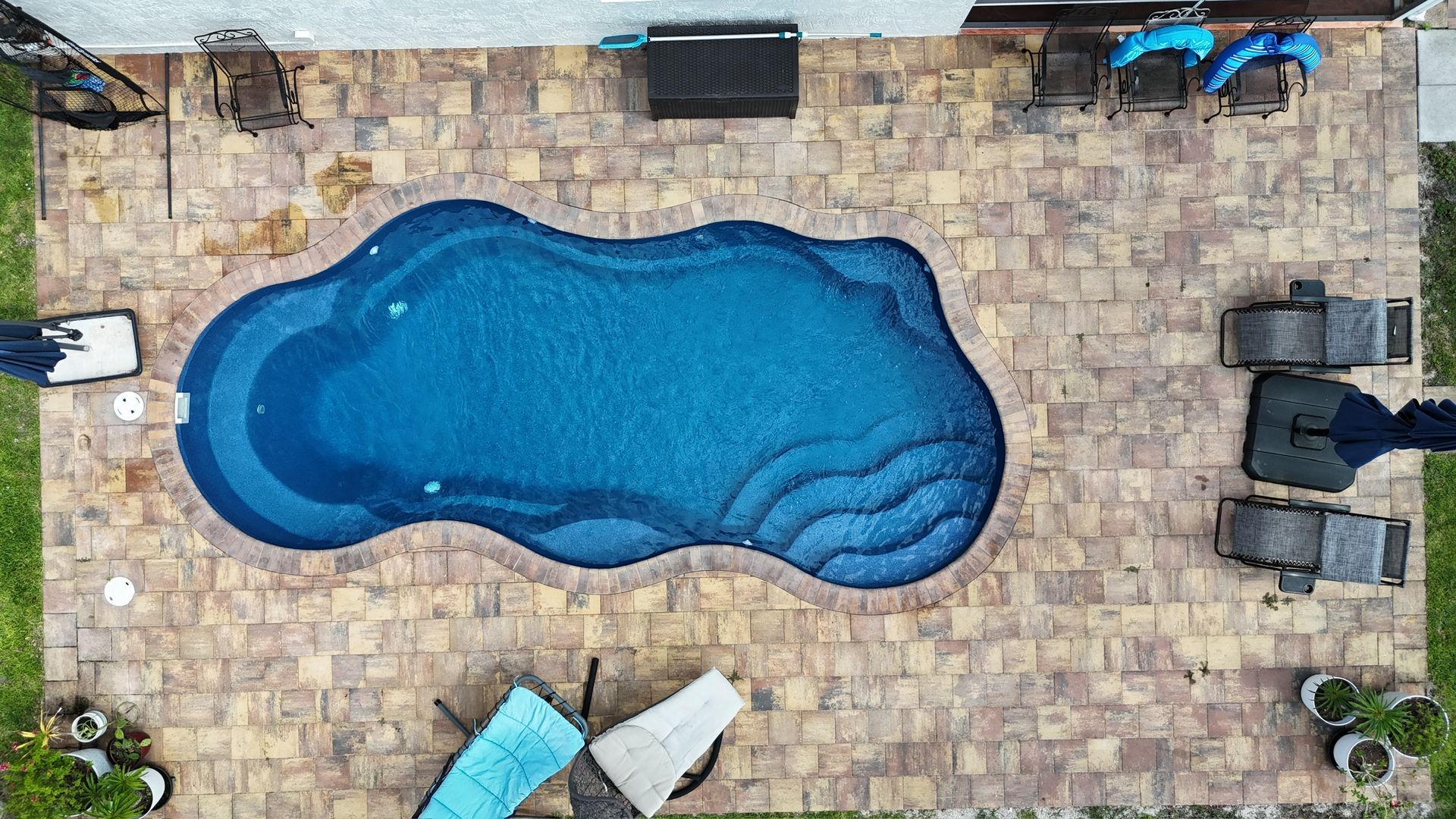 An aerial view of a large swimming pool surrounded by chairs and umbrellas.
