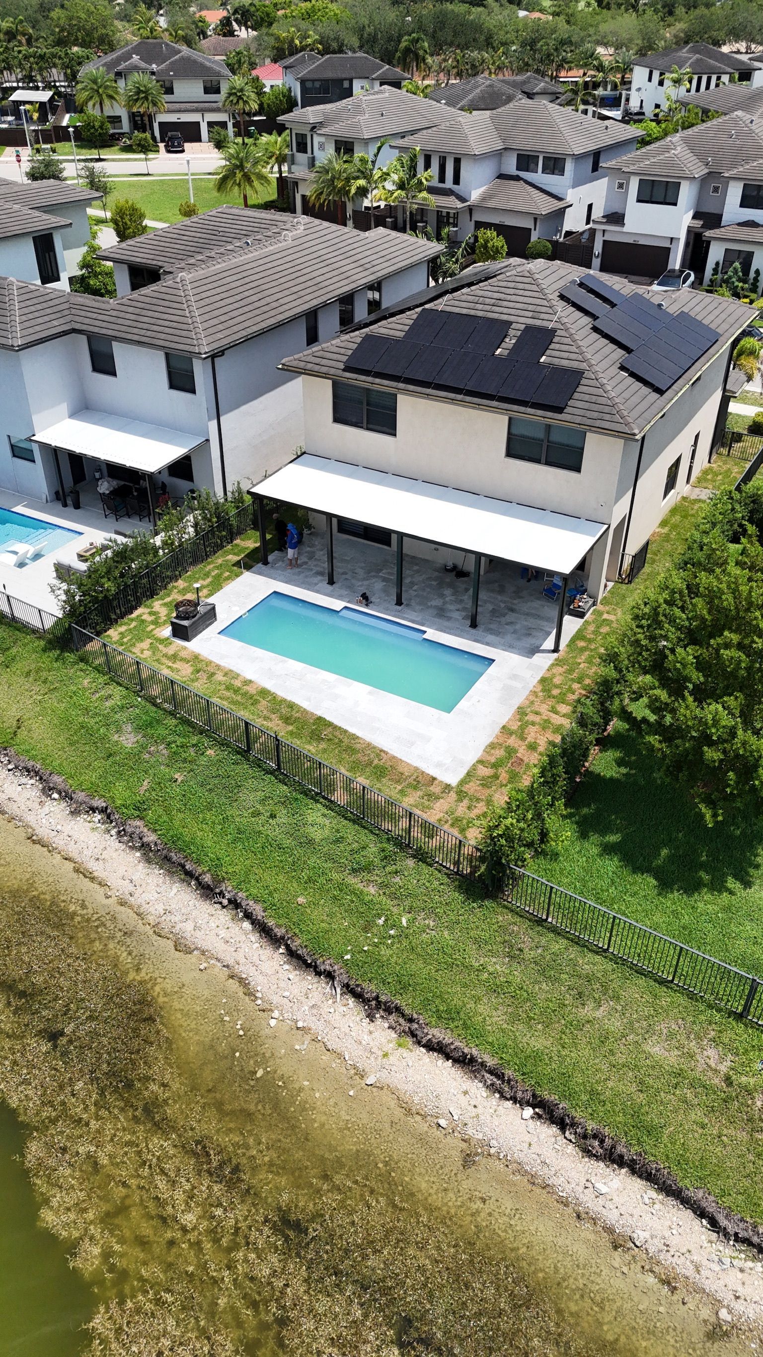 An aerial view of a house with a pool and solar panels on the roof.