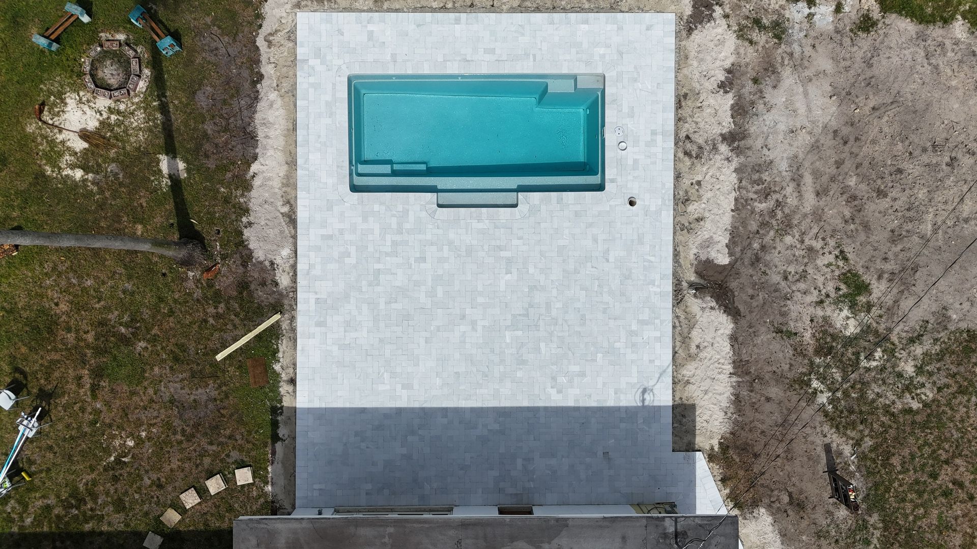 An aerial view of a swimming pool in the middle of a yard.