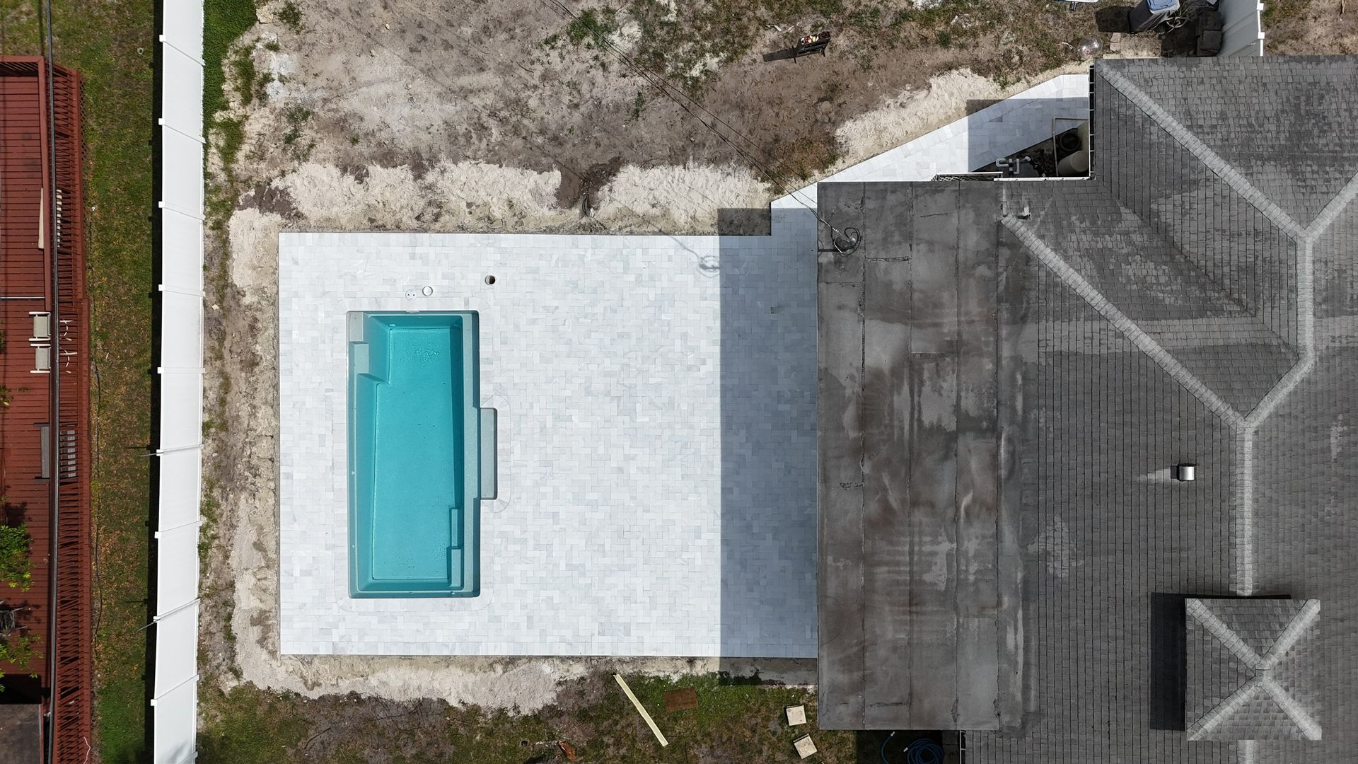 An aerial view of a swimming pool in the backyard of a house.