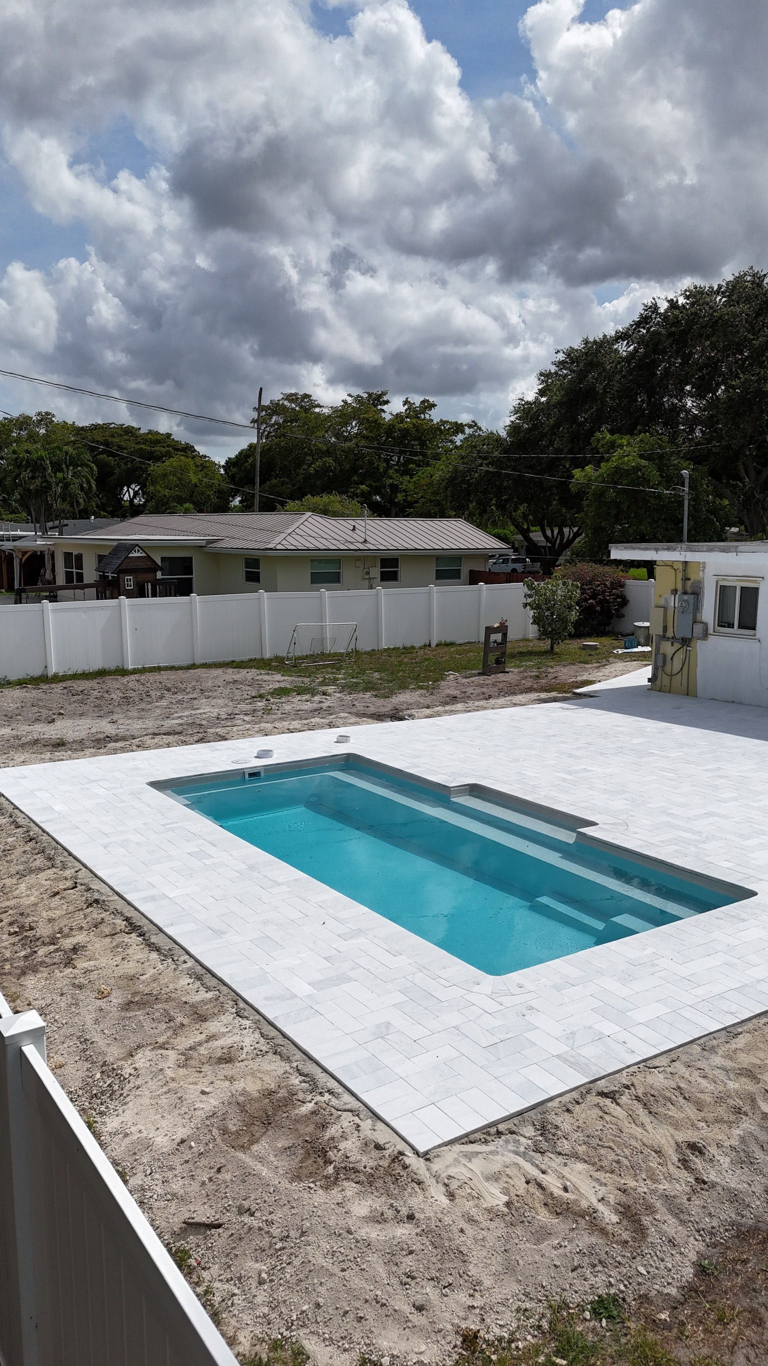 A swimming pool is being built in the backyard of a house.
