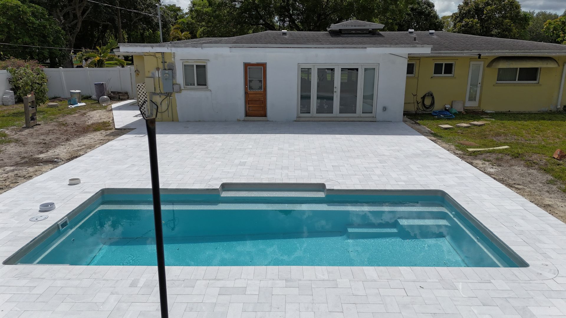 A large swimming pool is in the backyard of a house.