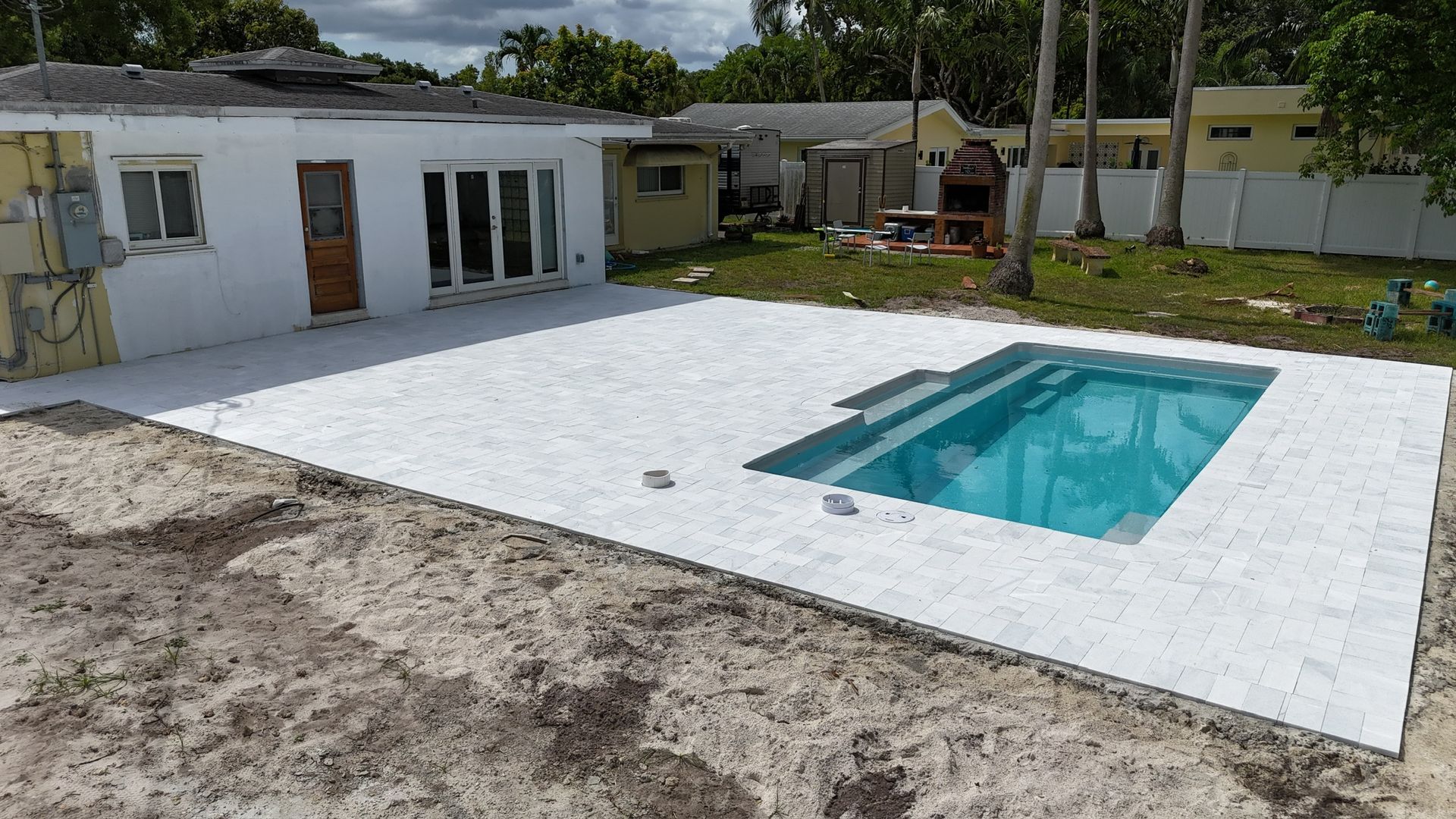 A swimming pool is in the backyard of a house