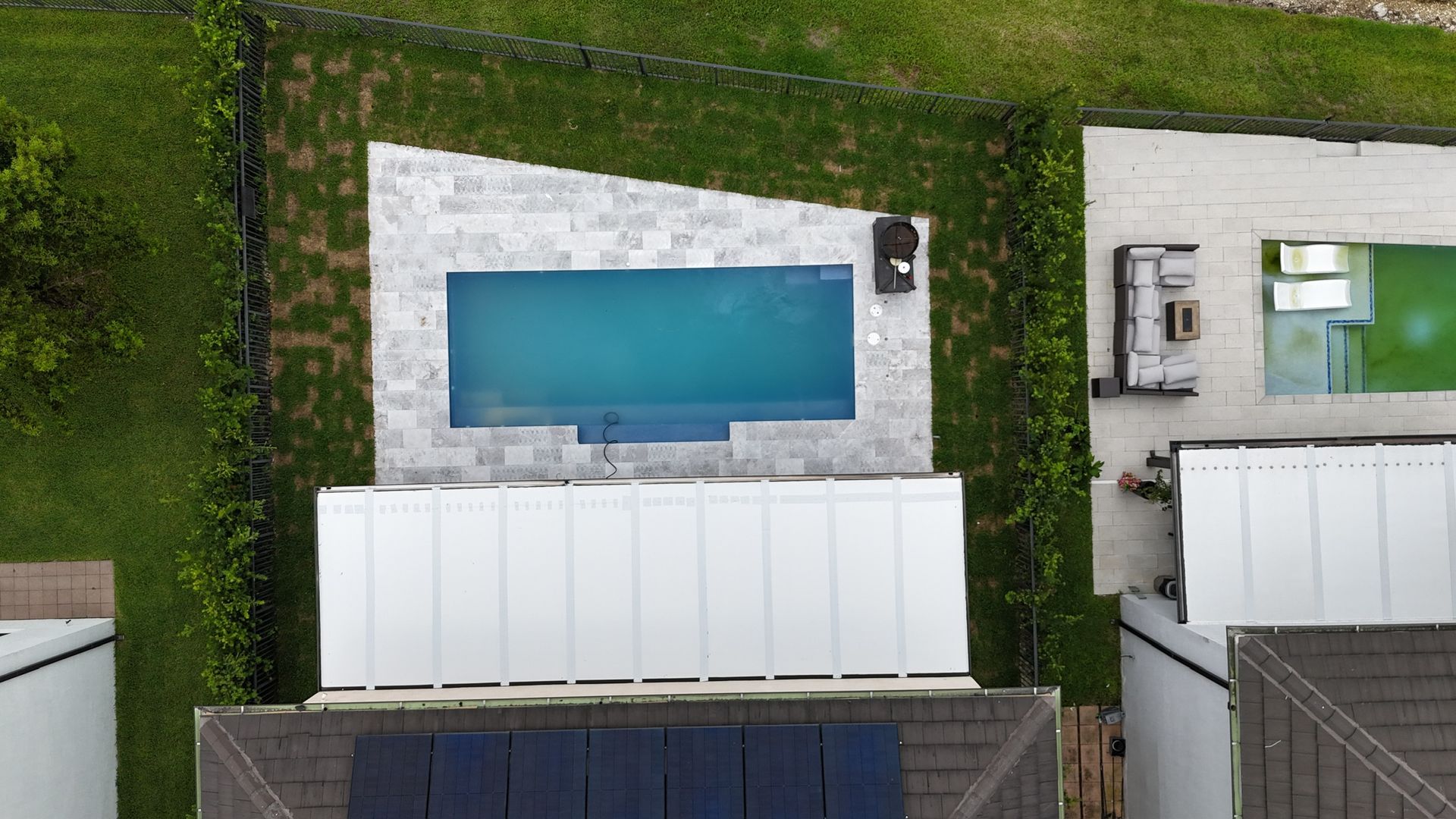 An aerial view of a house with a large swimming pool