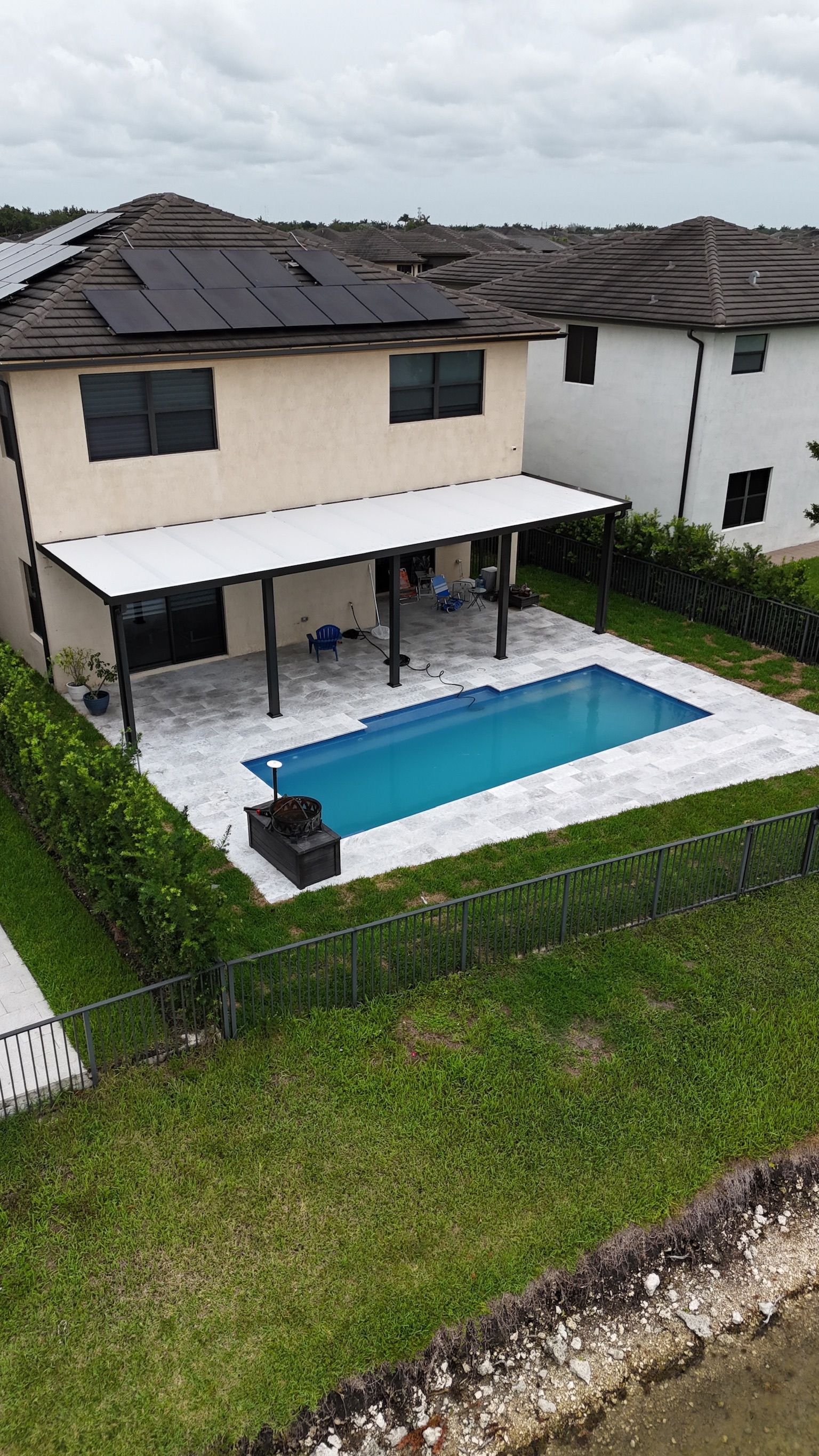 An aerial view of a house with a large swimming pool in the backyard.