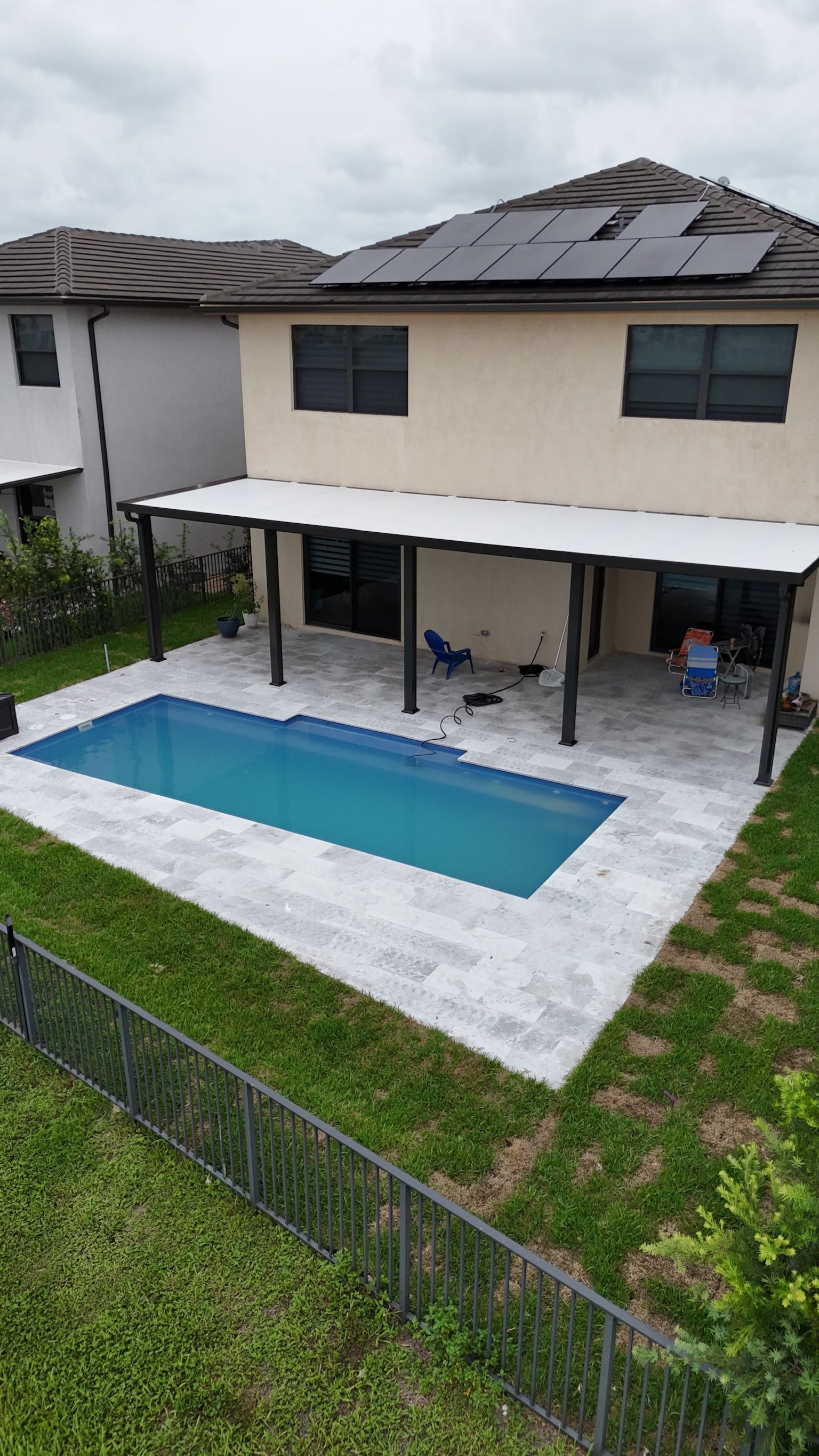 An aerial view of a house with a large swimming pool in the backyard.
